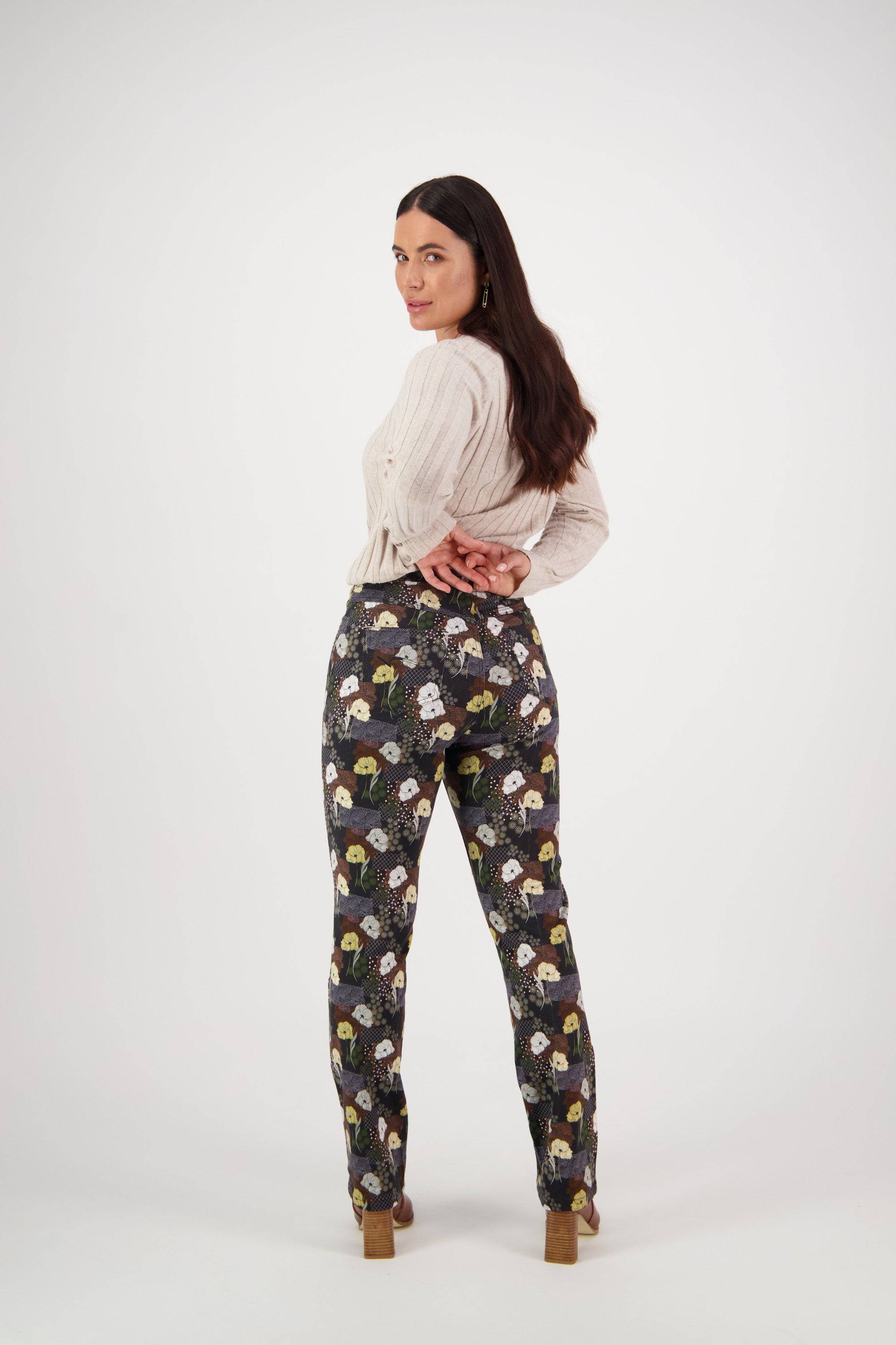 Woman standing with hands behind her back, wearing a beige sweater and Vassalli Bay Pull On - Karma slim leg pants with stretch fabric. She looks over her shoulder in heeled shoes against a white background.