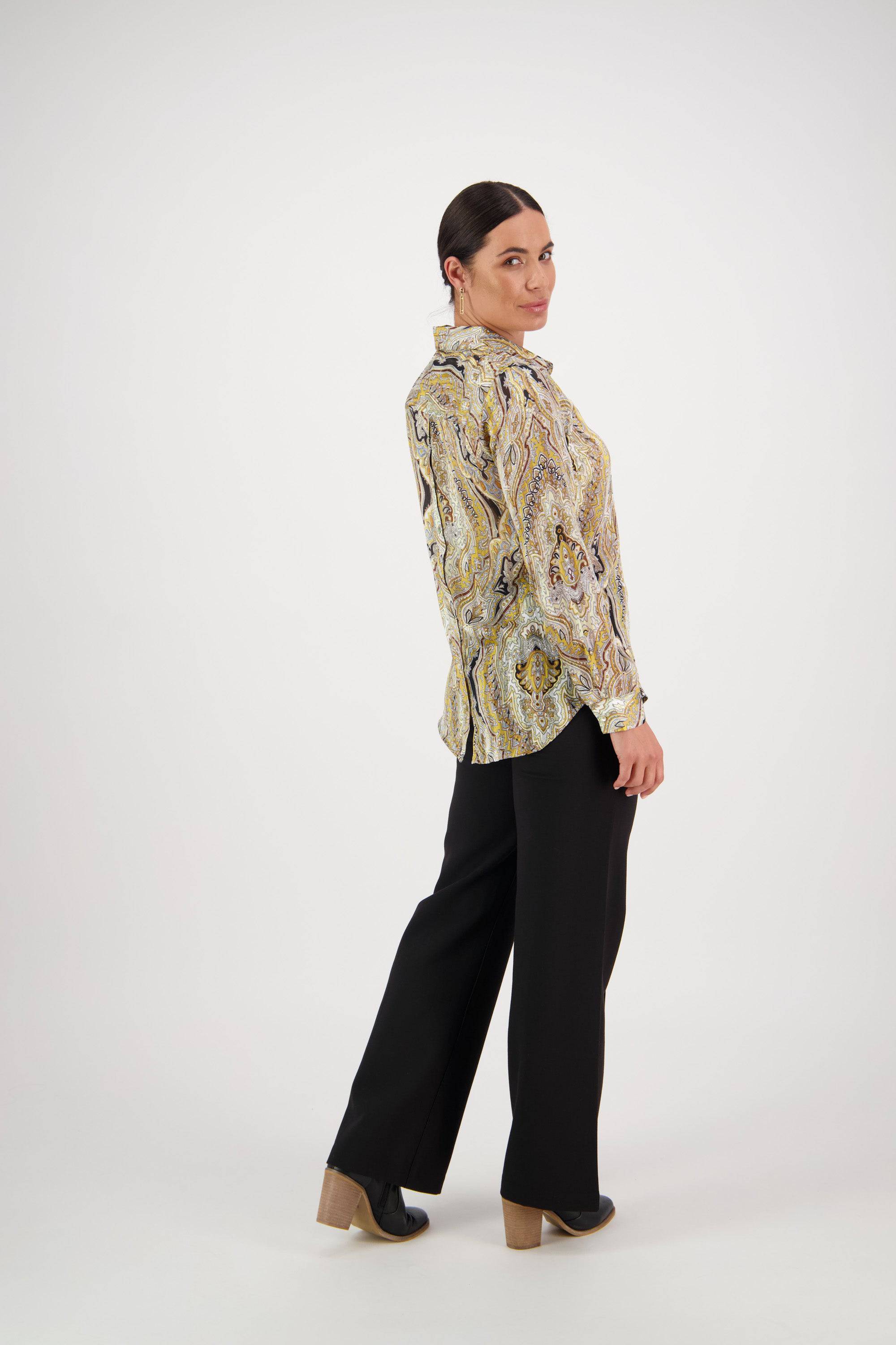 A person with dark hair pulled back wears the Vassalli Ballot Shirt - Majestic with gold lurex stripes, paired with black wide-leg pants and heeled shoes, standing sideways and looking over their shoulder against a light background.