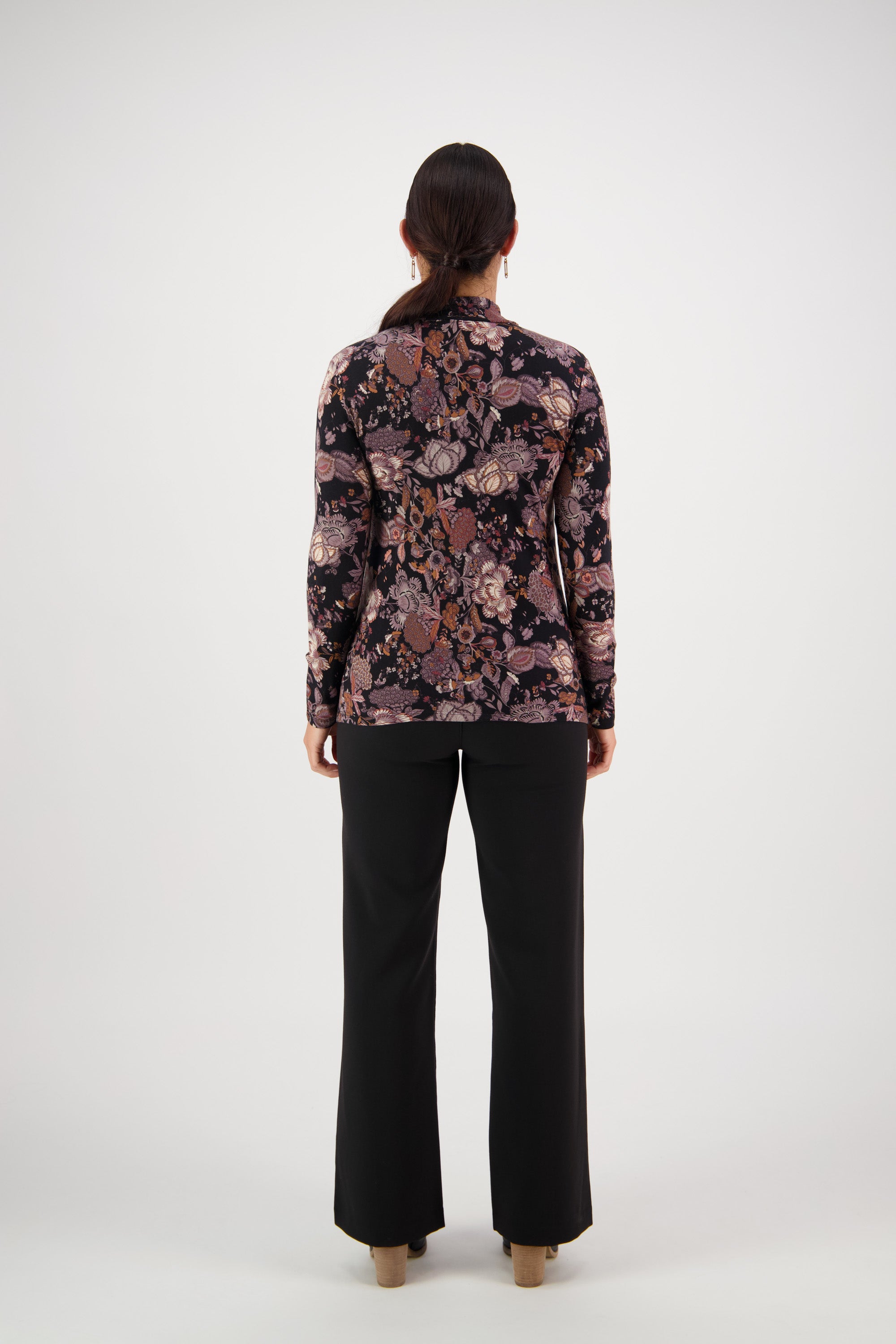 A person with long dark hair, seen from behind, wears the Vassalli Foundation Top - Vintage with black pants, standing against a plain white background.