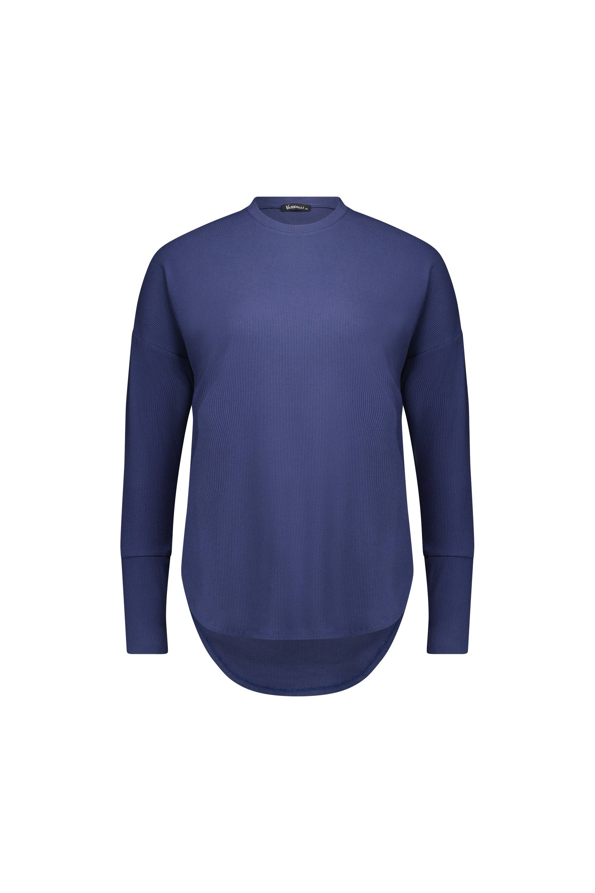 The Vassalli Round Neck Top in denim blue features a relaxed fit, long sleeves, and a curved hem, shown against a plain white background.
