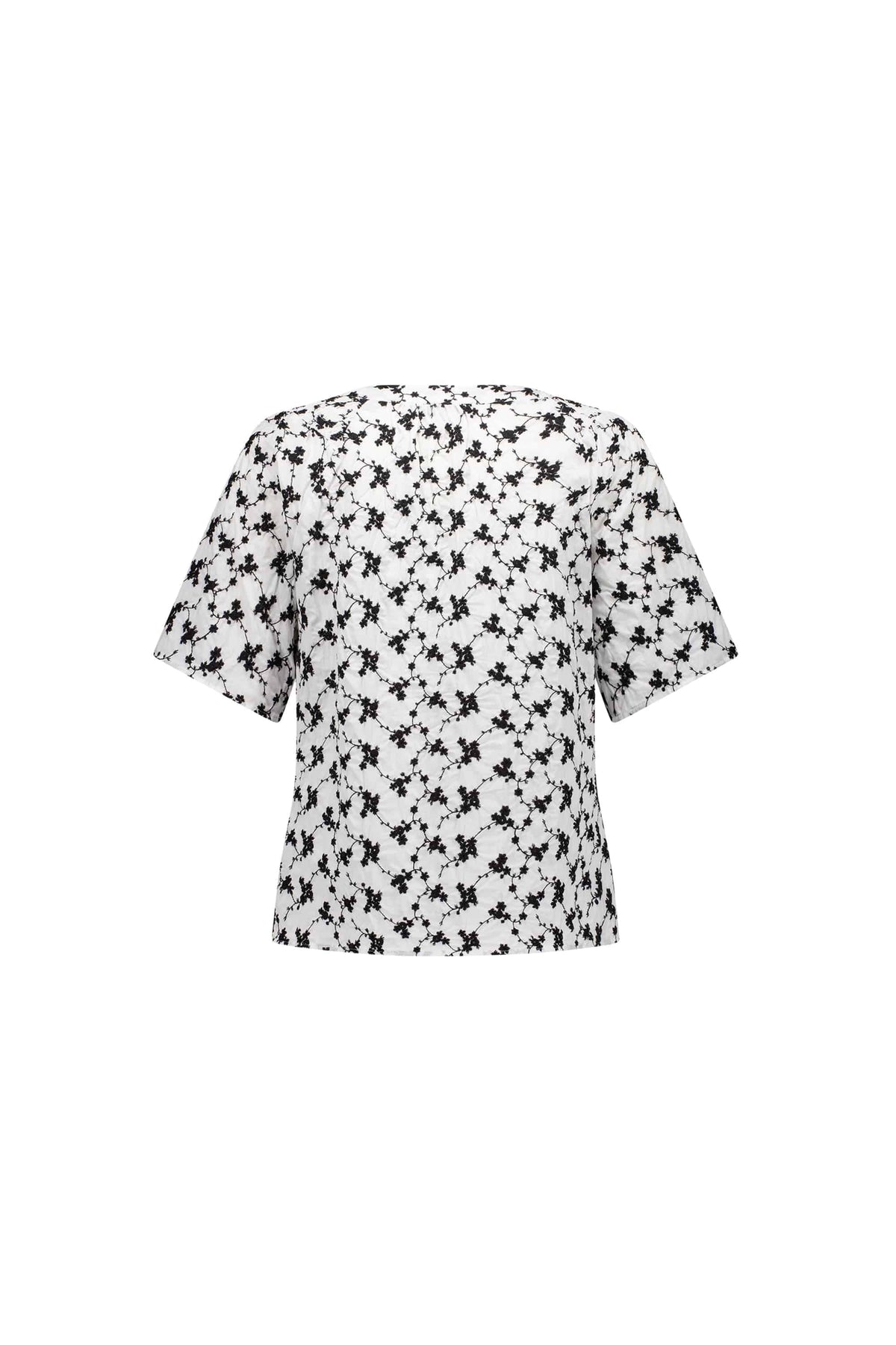 The Vassalli V-Neck Top - Floral is a short-sleeved, loose-fit white blouse with an all-over black abstract print, shown from the back on a plain white background.