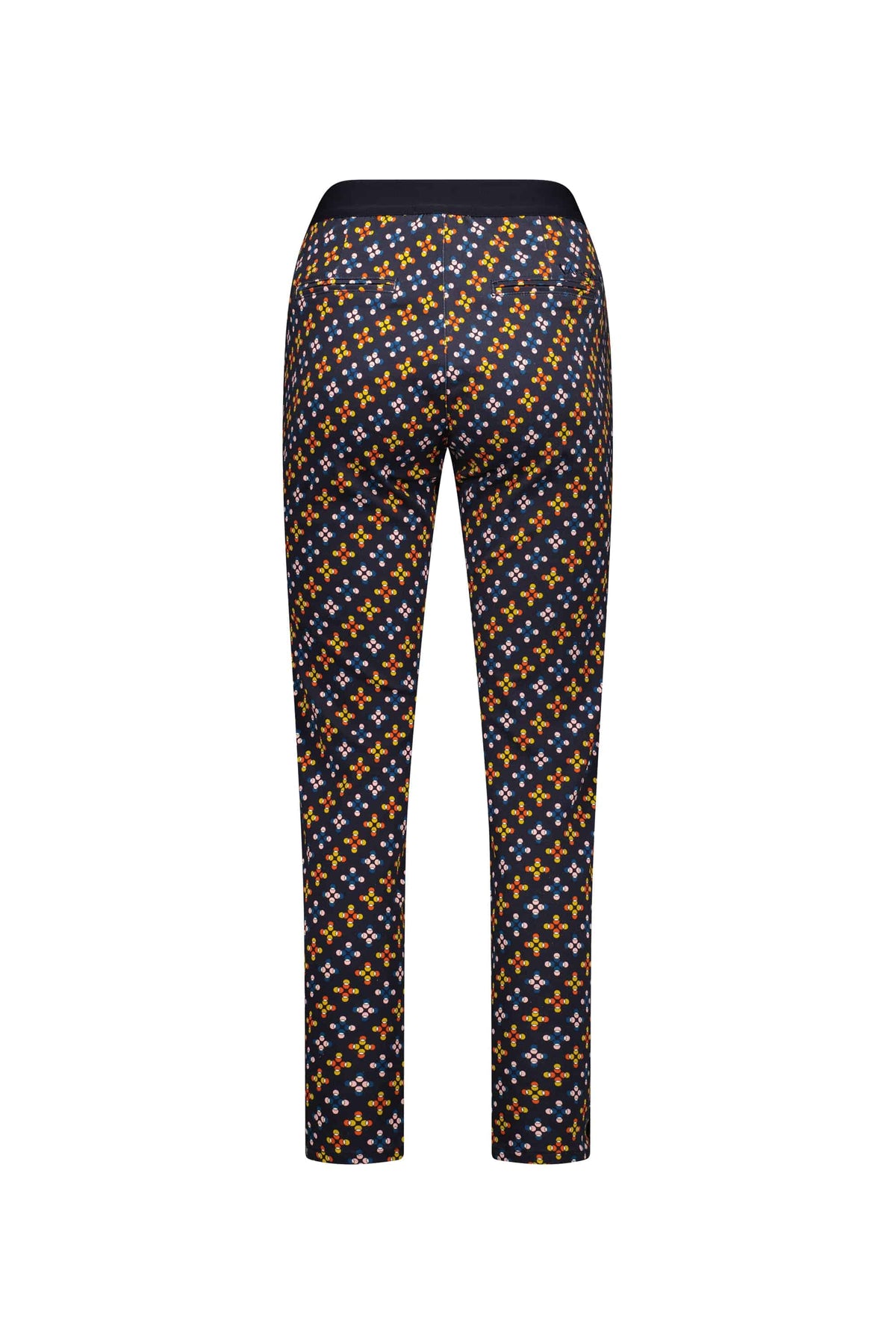 Back view of the Vassalli Ankle Grazer Pant - Stellar, featuring a bold geometric print with orange, yellow, and blue accents on dark stretch fabric. Includes a solid black waistband and skinny leg design for a modern look.