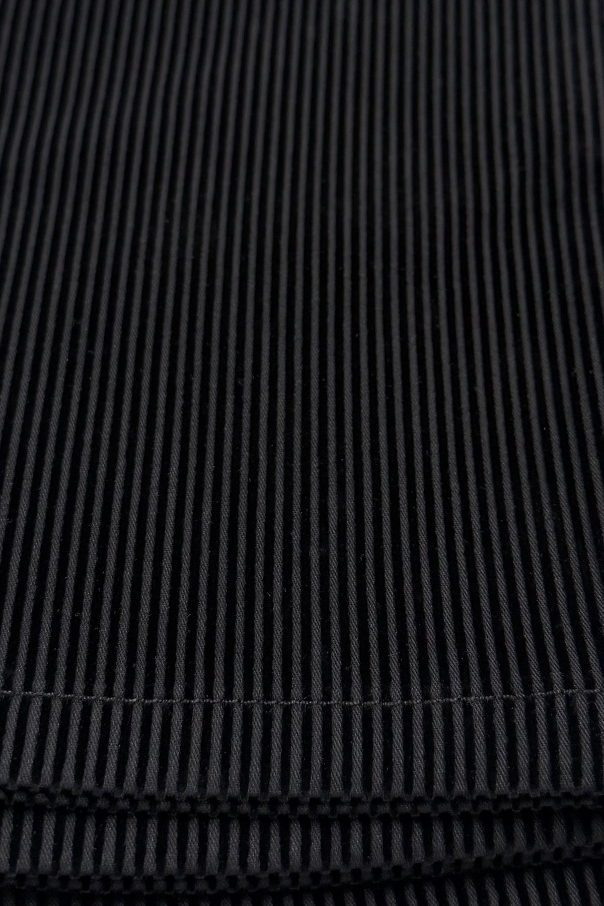 Close-up of the Vassalli Bay Pull On - Black/Black Stripe, highlighting the textured vertical ridges and visible stitching of its black corduroy fabric—perfect for pull-on pant styles that offer both comfort and timeless style.