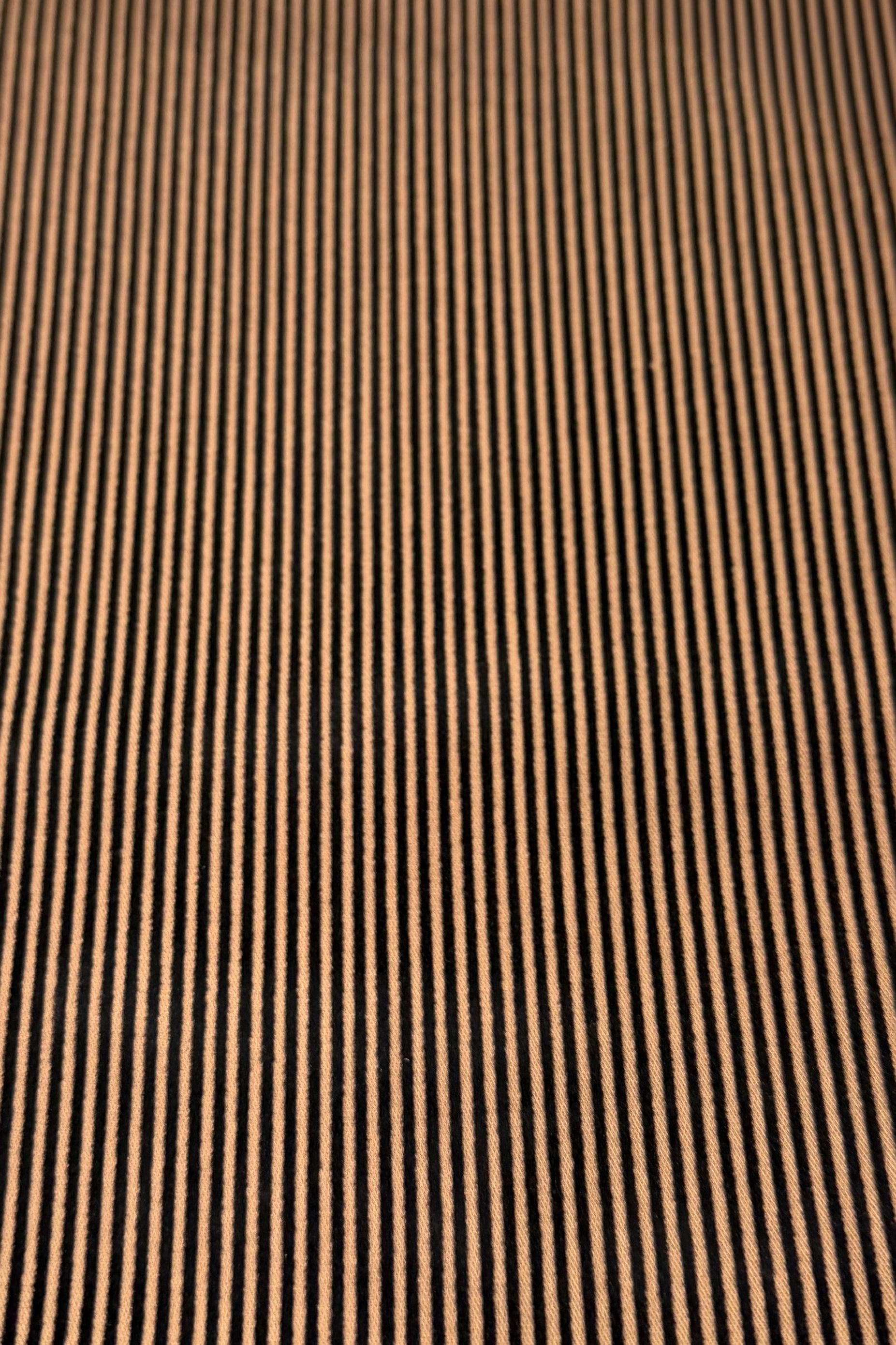 A close-up view of the Vassalli Bay Pull On in Bronze/Black Stripe reveals stretch fabric featuring narrow, evenly spaced vertical black and bronze stripes for a visually textured pattern, commonly used in slim leg pants to create a sleek pull-on silhouette.