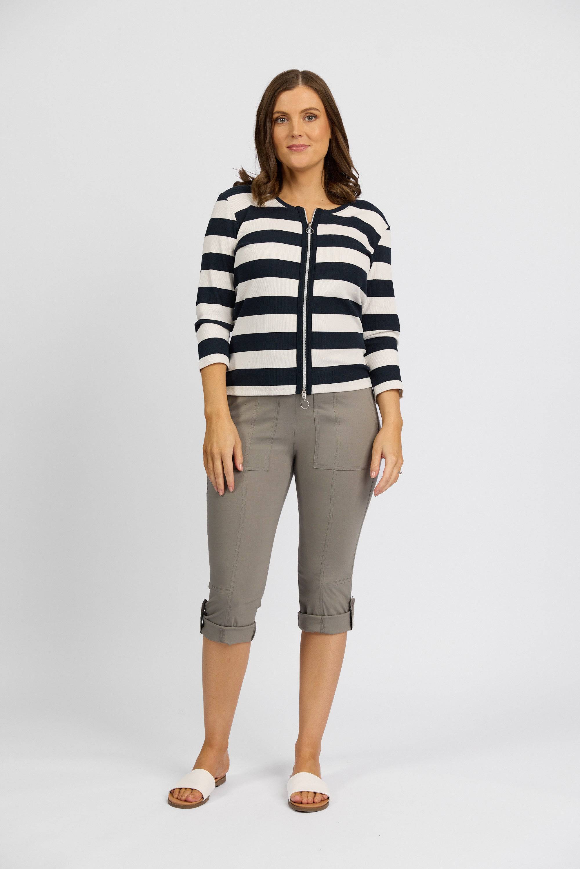 A woman faces forward in a black and white striped long-sleeve top, Vassalli Paris 3/4 Cargo Short in Latte with cuffed hems, and white slide sandals, set against a plain white background.