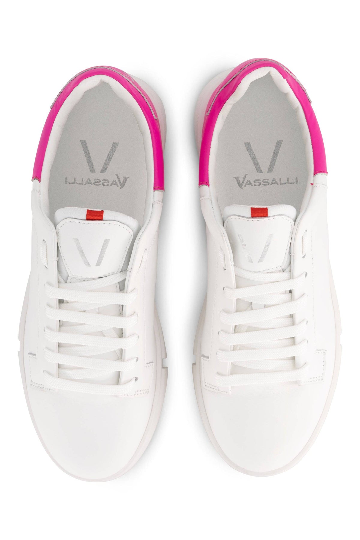 The Vassalli VS-001 White/Fuchsia laced sneakers feature a leather upper with pink heel accents and a red tongue tab, plus light gray insoles displaying the Vassalli brand name in gray text.