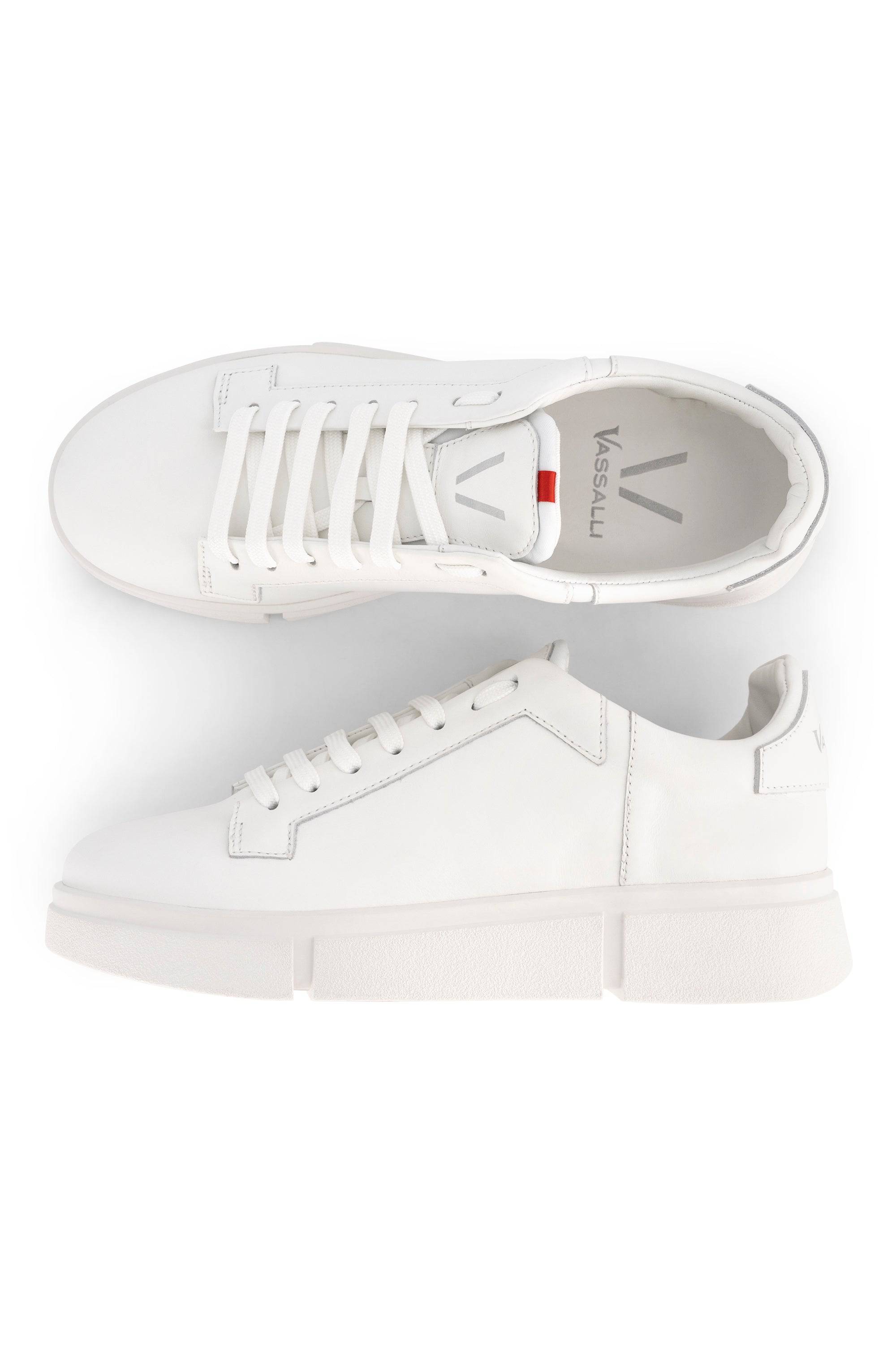 The Vassalli VS-001 White/White Laced Sneaker features a minimalist design with white laces, a thick white sole, and is shown from top and side views. The Vassalli brand name appears on both the insole and heel.