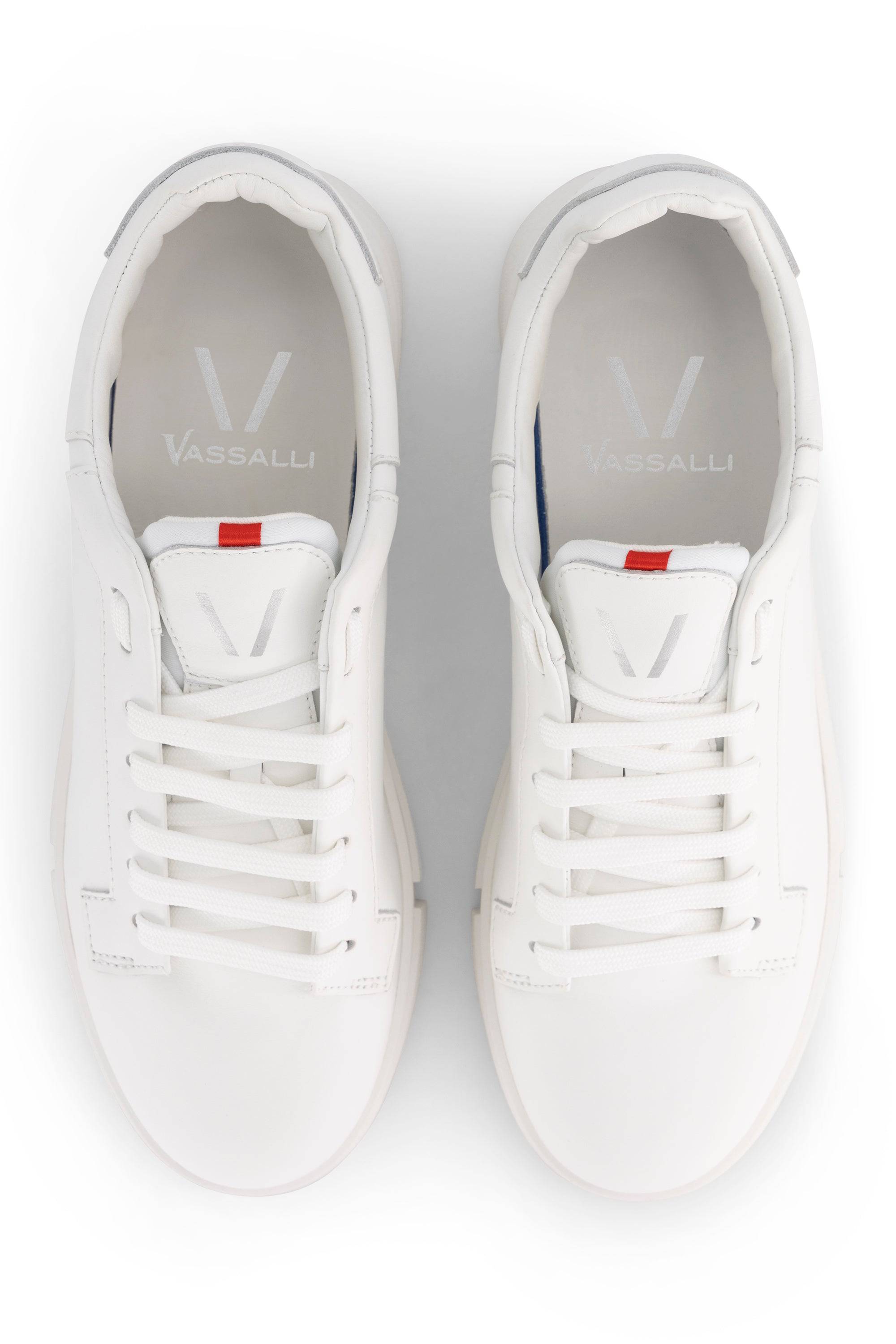 A pair of Vassalli VS-001 White/White laced sneakers in leather, seen from above, featuring white laces, a subtle red tab on the tongue, and the Vassalli logo printed inside each shoe.