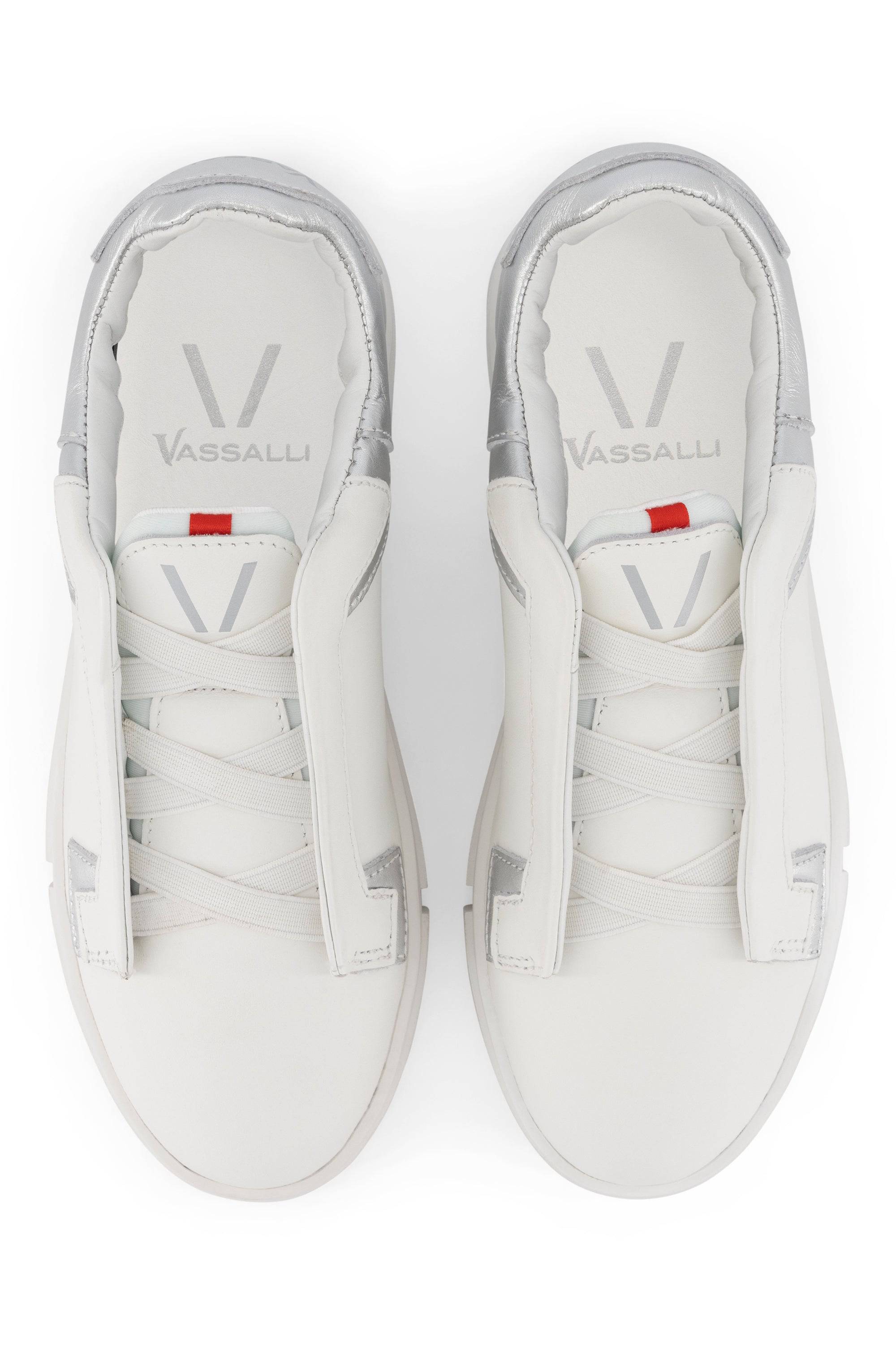 The VS-004 White/Silver Laceless Sneakers by Vassalli are shown from above, displaying silver-accented heels, wide white tongues with small red tabs, and clean leather platforms arranged neatly side by side.