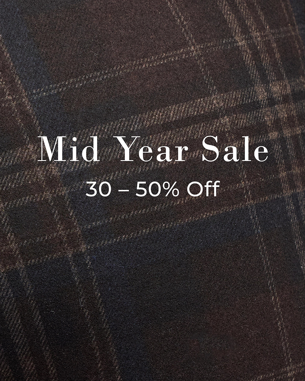 A close-up of a dark plaid fabric with white text reading 'Mid Year Sale' and '30 - 50% Off' overlaid in the center.