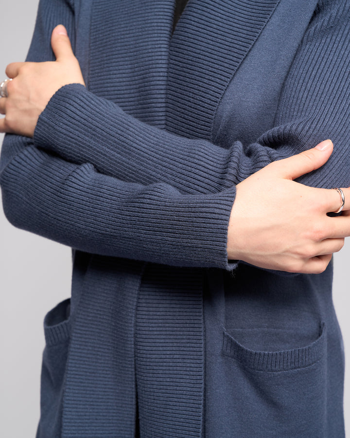 A person models the Vassalli Downtown Cardi - Marine in blue, arms crossed with hands and a silver ring visible, against a plain light background.