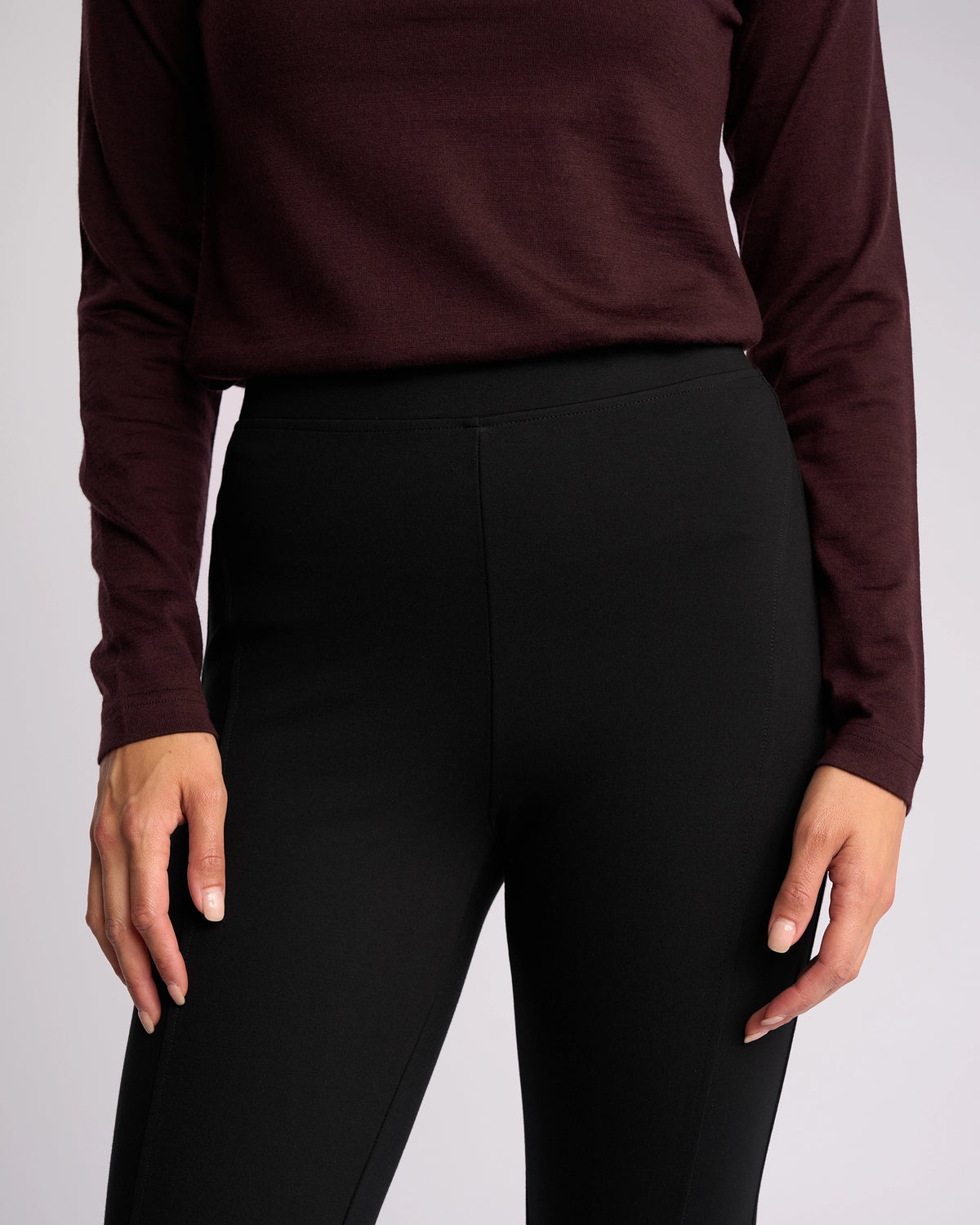 A person wears the Vassalli Toll Ponti Pant in black, a high-rise skinny-leg pant in stretch ponti, paired with a long-sleeve dark burgundy top; shown from shoulders to mid-thigh with arms relaxed at their sides.