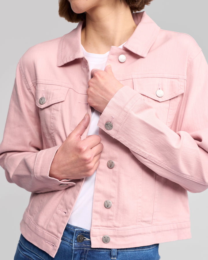 A person, head partially out of frame, buttons up the Vassalli Ratio Jacket - French Rose Denim over a white shirt and blue jeans, set against a plain gray background.