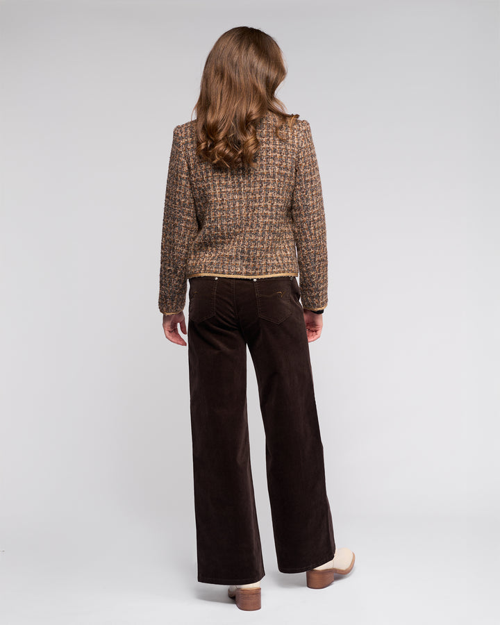 A woman with long brown hair, seen from behind, wears the Vassalli Stage Jacket - Florence with dark brown wide-leg pants and beige platform shoes against a plain light background.