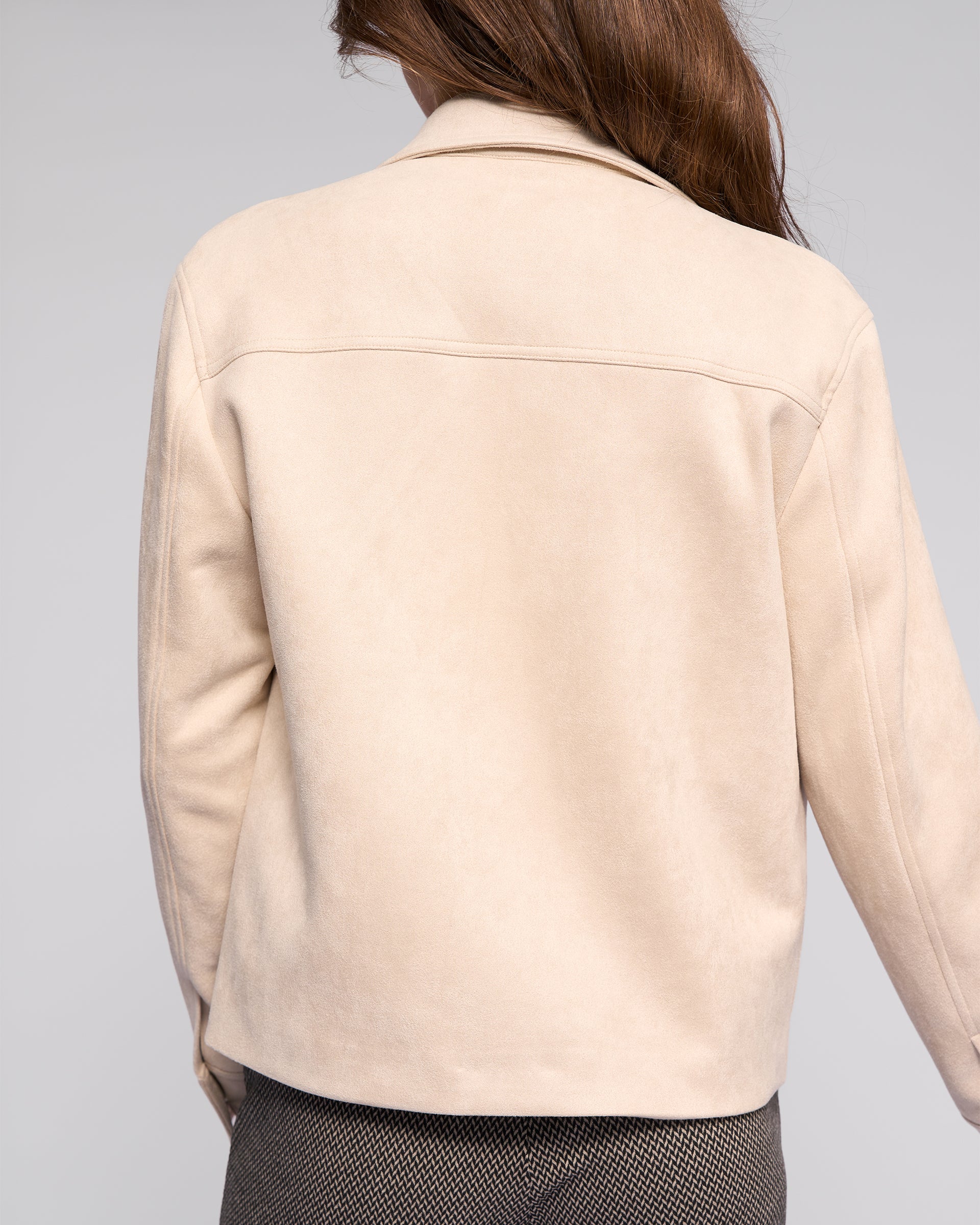 A person with long brown hair is shown from the back, wearing the Vassalli Guest Jacket - Bone and gray textured pants against a plain light gray background.