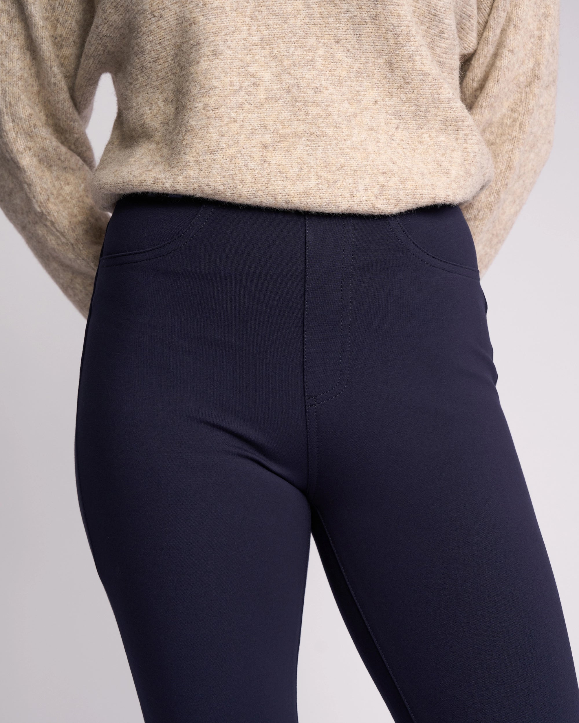 A person wears a beige sweater with Vassalli’s Bay Ponti Pull On - Navy slim-leg pants. The cropped image showcases the comfort and versatility of these workwear pants against a plain background.