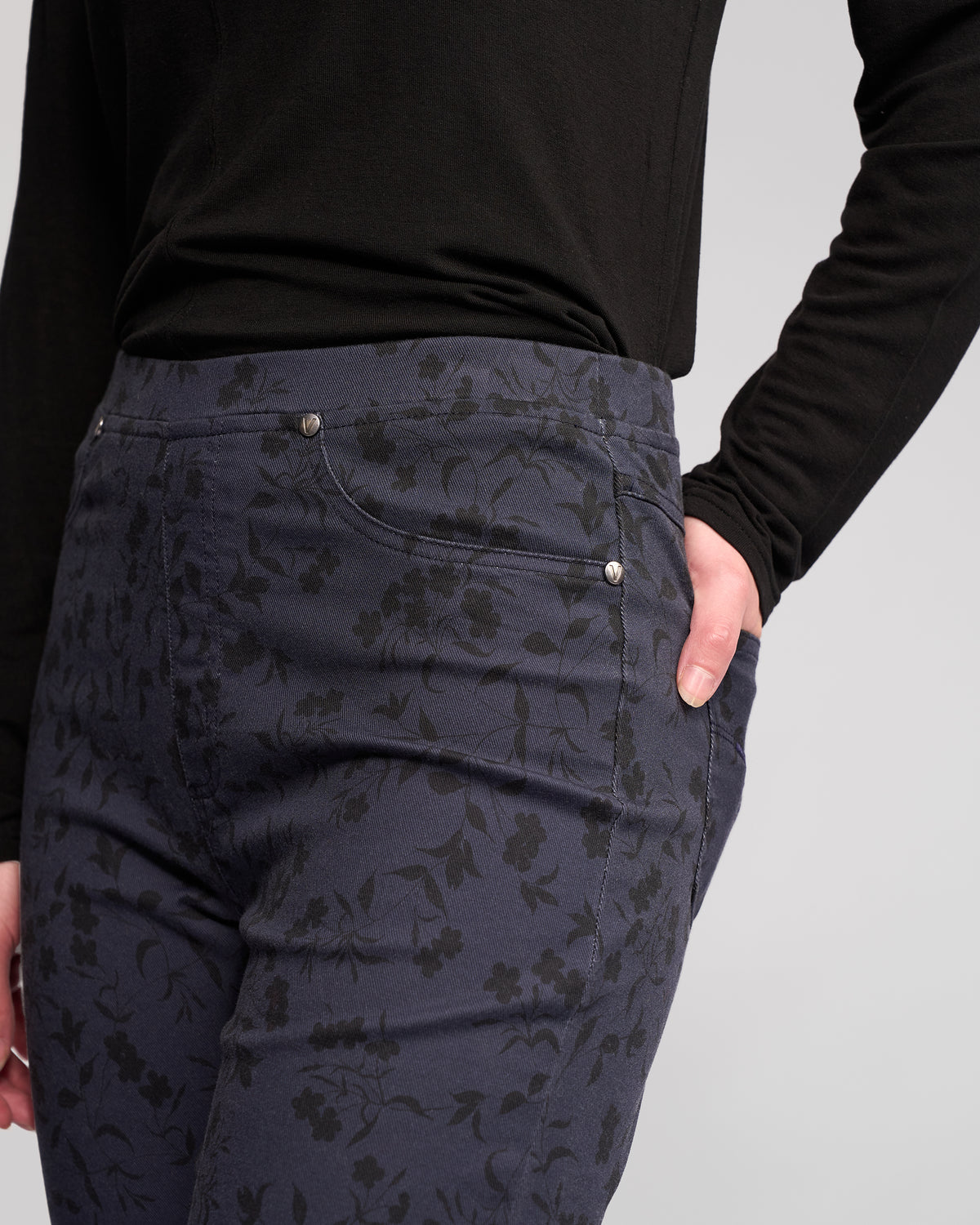 Model wearing Vassalli Bay Pull On - Noir pants and a long-sleeve black top, right hand in pocket, shown from mid-torso to mid-thigh against a plain light background.