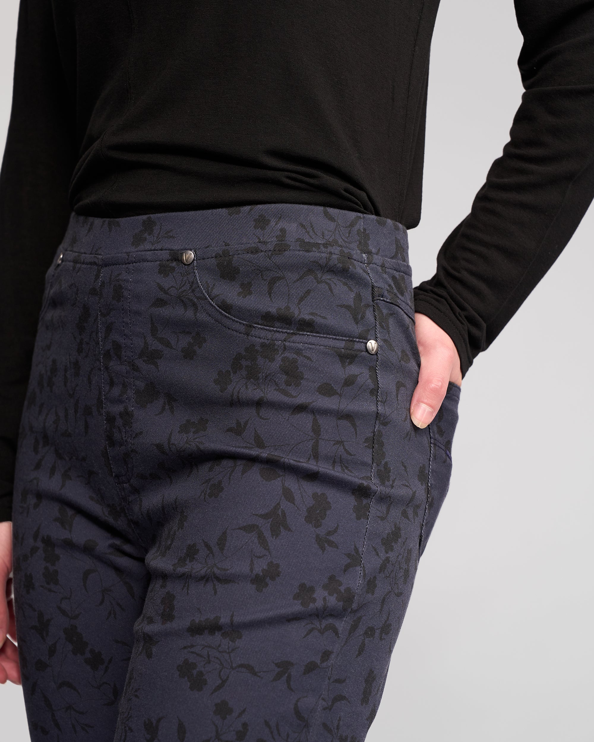 Model wearing Vassalli Bay Pull On - Noir pants and a long-sleeve black top, right hand in pocket, shown from mid-torso to mid-thigh against a plain light background.