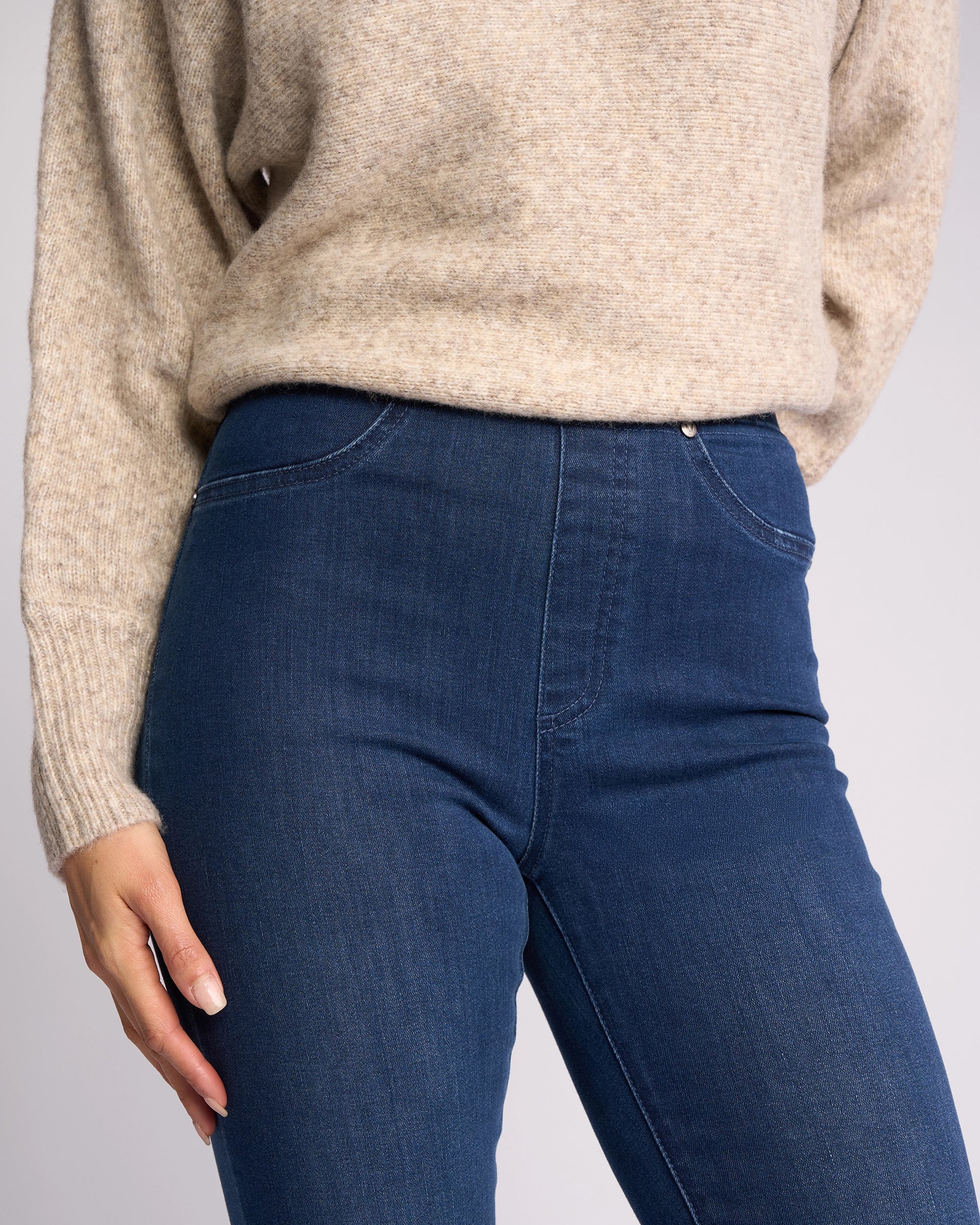 A person wears Vassalli's Bay Pull On - Blue Denim (With Front Fade), paired with a beige knit sweater. The cropped image focuses on the torso and upper legs, with one hand resting near the hip.