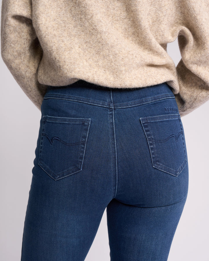 A person is seen from the back wearing Vassalli's Bay Pull On - Blue Denim (With Front Fade), highlighting the slim-leg jean’s pockets and waistband.