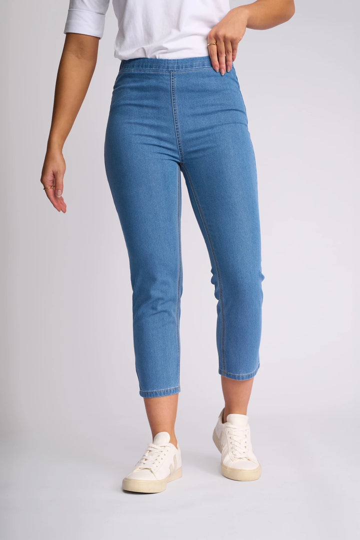A person wearing a white shirt, the Vassalli Harbour 7/8 Pant - Light Denim (Contrast Stitch), and white sneakers stands against a plain light background. Only the lower half of the body is visible.