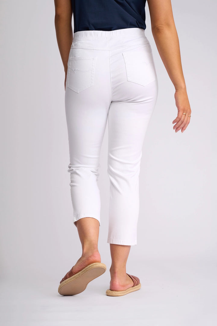A person is shown from the back, walking away on a plain light background, wearing the Vassalli Harbour 7/8 Pant in White, paired with a navy top and tan sandals.