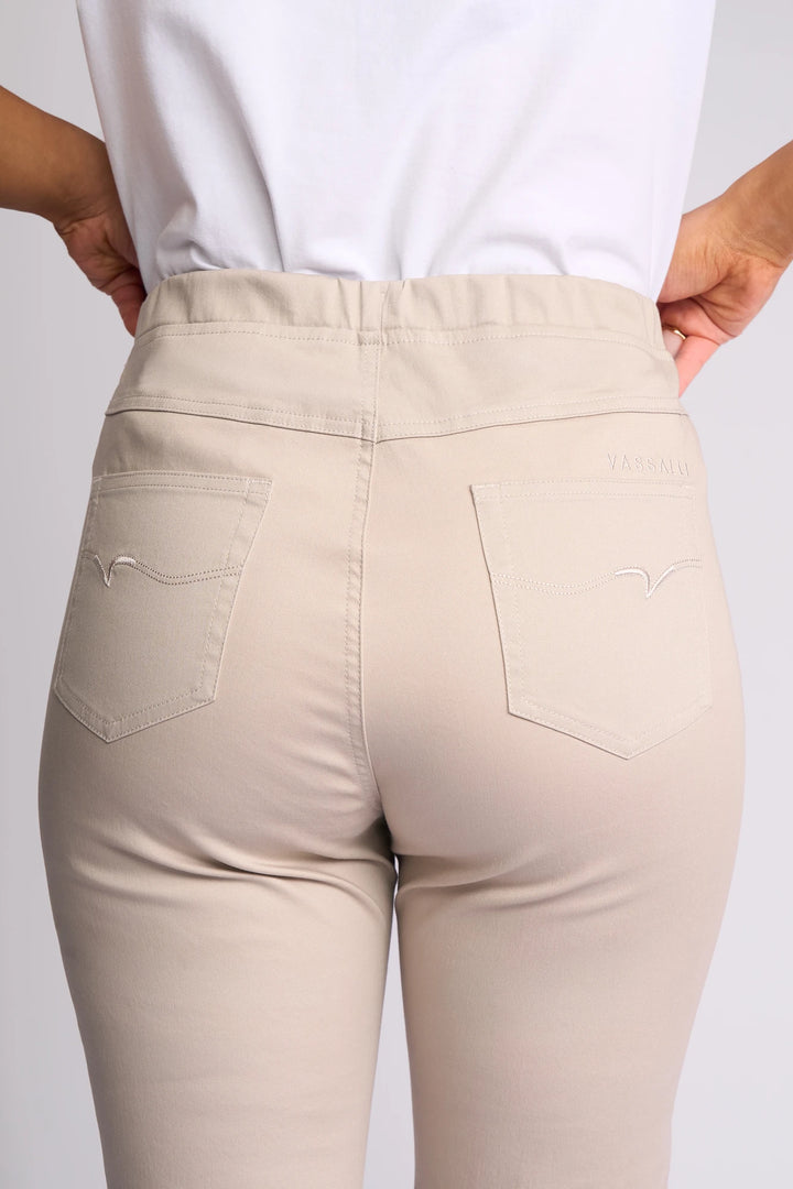 A person, shown from the back with hands on their hips, is wearing the Vassalli Sierra 7/8 Pant in Pumice. The slim-leg pants feature two back pockets with stitched designs and are crafted from comfortable stretch cotton for ease of movement.