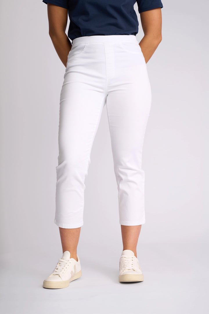 A person wearing a navy blue shirt, Vassalli Sierra 7/8 Pant in White, and beige sneakers stands against a plain light background.