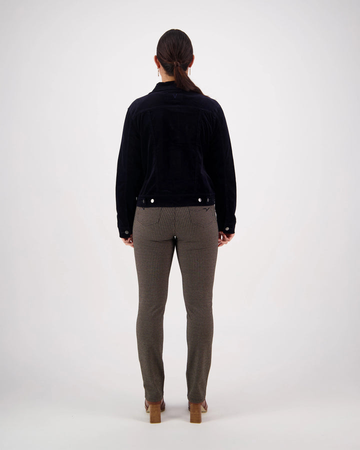 A woman stands facing away from the camera against a plain white background, wearing the Vassalli Core Cord Jacket - Midnight—a timeless wardrobe staple.