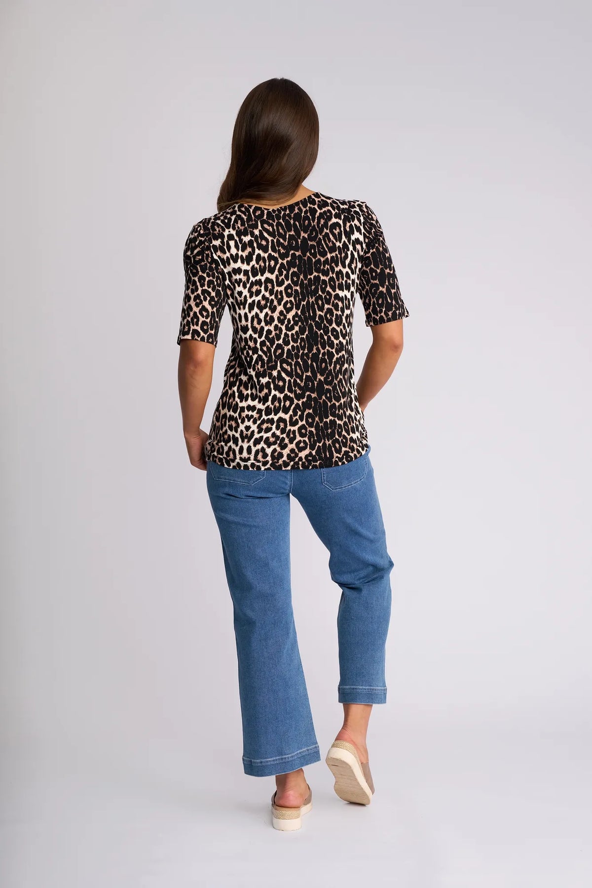 Back view of a person wearing a Carmen Top - Leopard short-sleeved top and blue jeans.