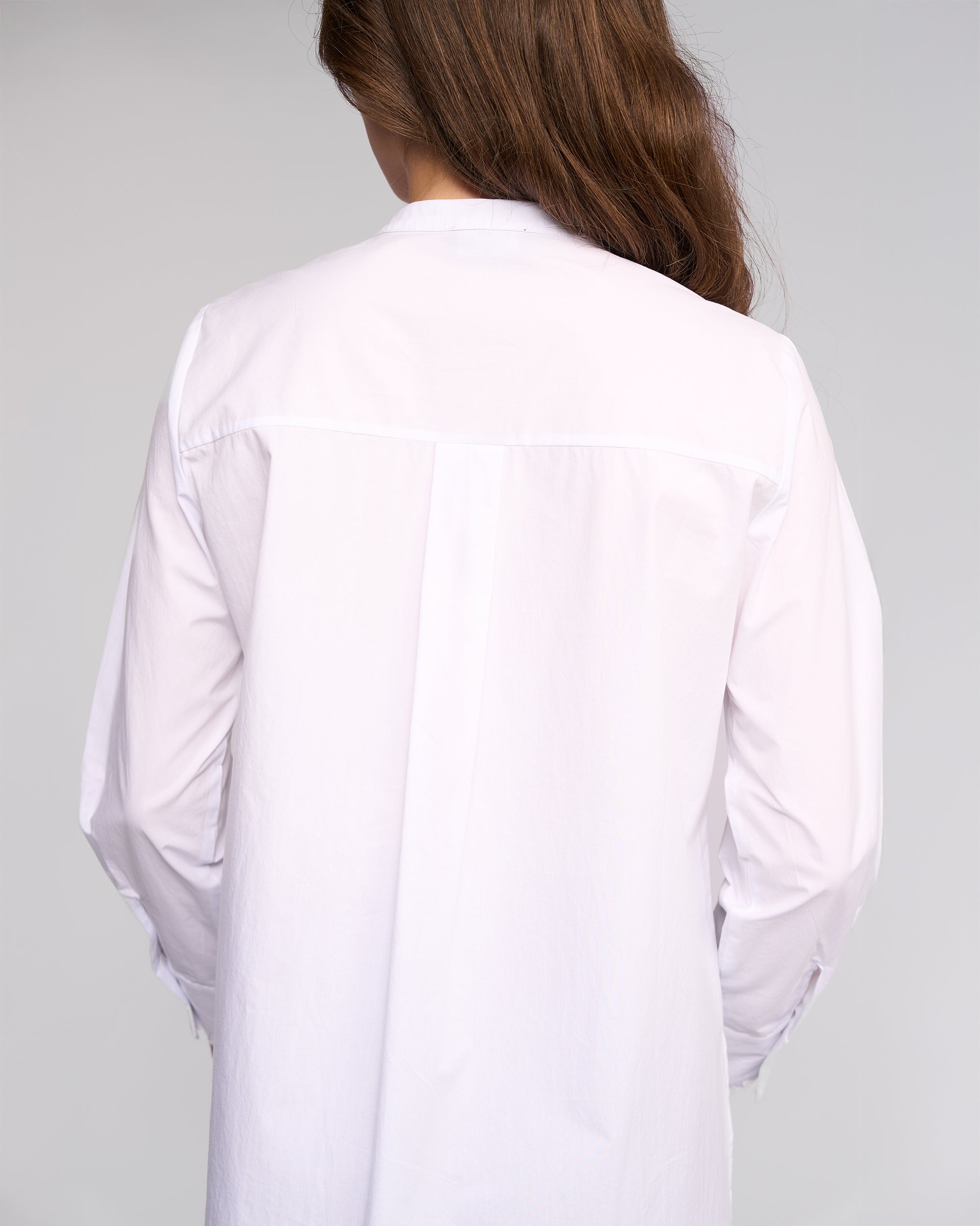 A person with long brown hair is shown from the back wearing the Vassalli Manhattan Shirt in white, set against a light gray background.