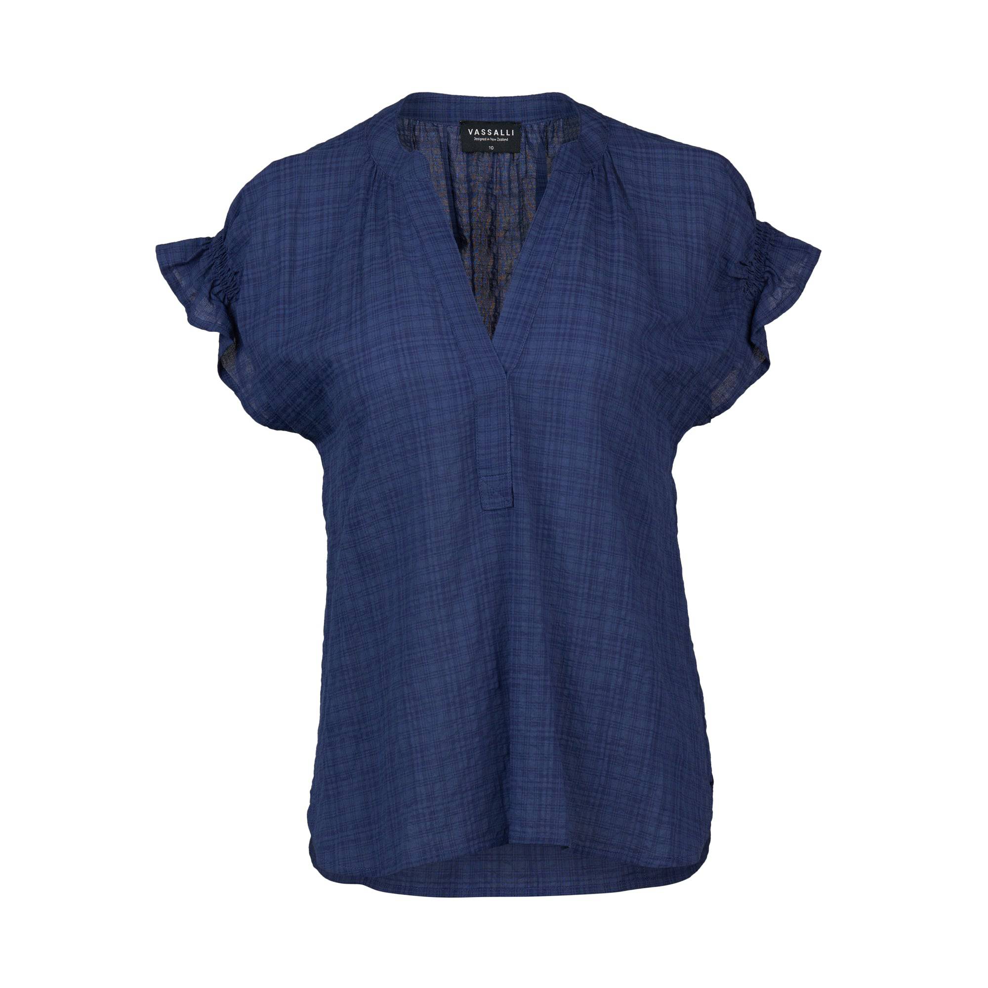 The Vassalli Evelyn Top in navy is a women's short-sleeved, V-neck top featuring a subtle checkered texture and ruffled sleeves, shown on a white background.