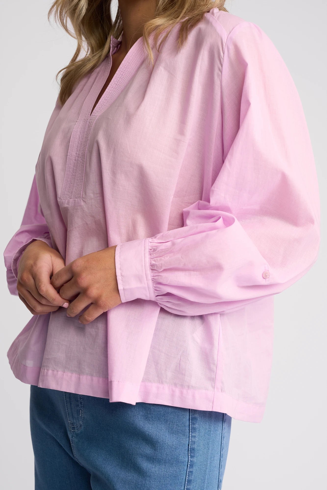 A person wearing a loose-fitting, long-sleeved Vassalli Lily Shirt in light purple with blue jeans, standing against a plain background. Only the torso and arms are visible.