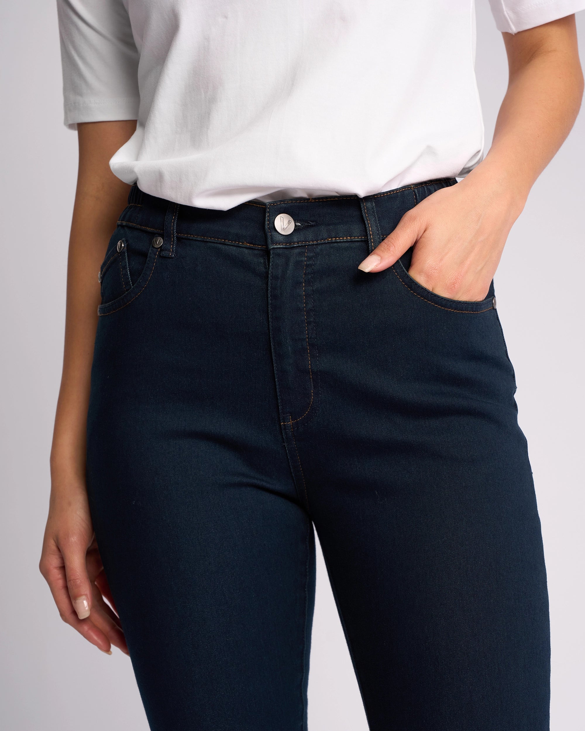 A person wearing a white short-sleeve shirt and Vassalli Mode Jean - Indigo Denim skinny jeans with one hand in their pocket, shown from shoulders to mid-thigh against a plain background.