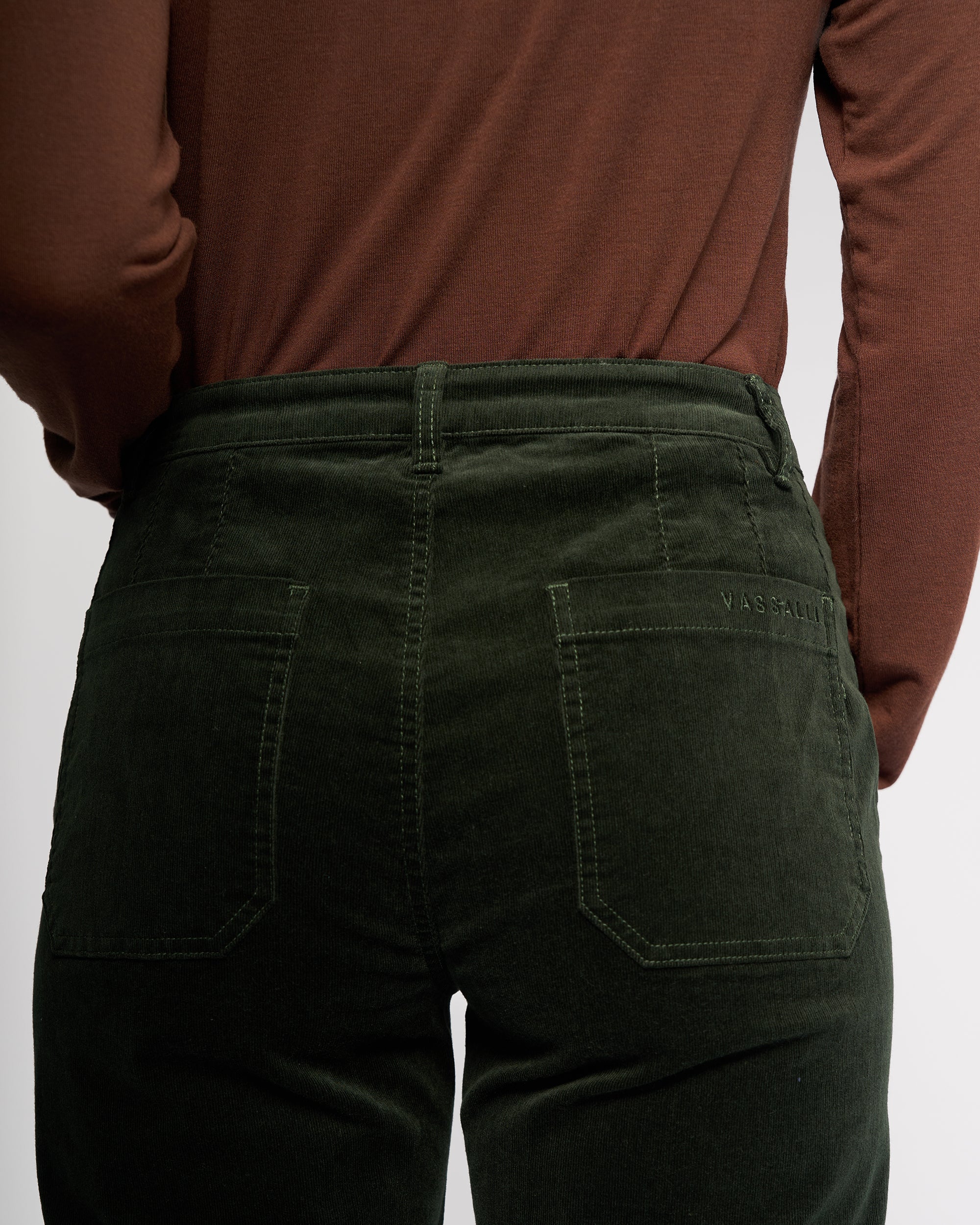 A person is shown from the back wearing a brown long-sleeve shirt and Vassalli’s Market Cord Pant in Forest, highlighting the waist and hips with visible back pockets.