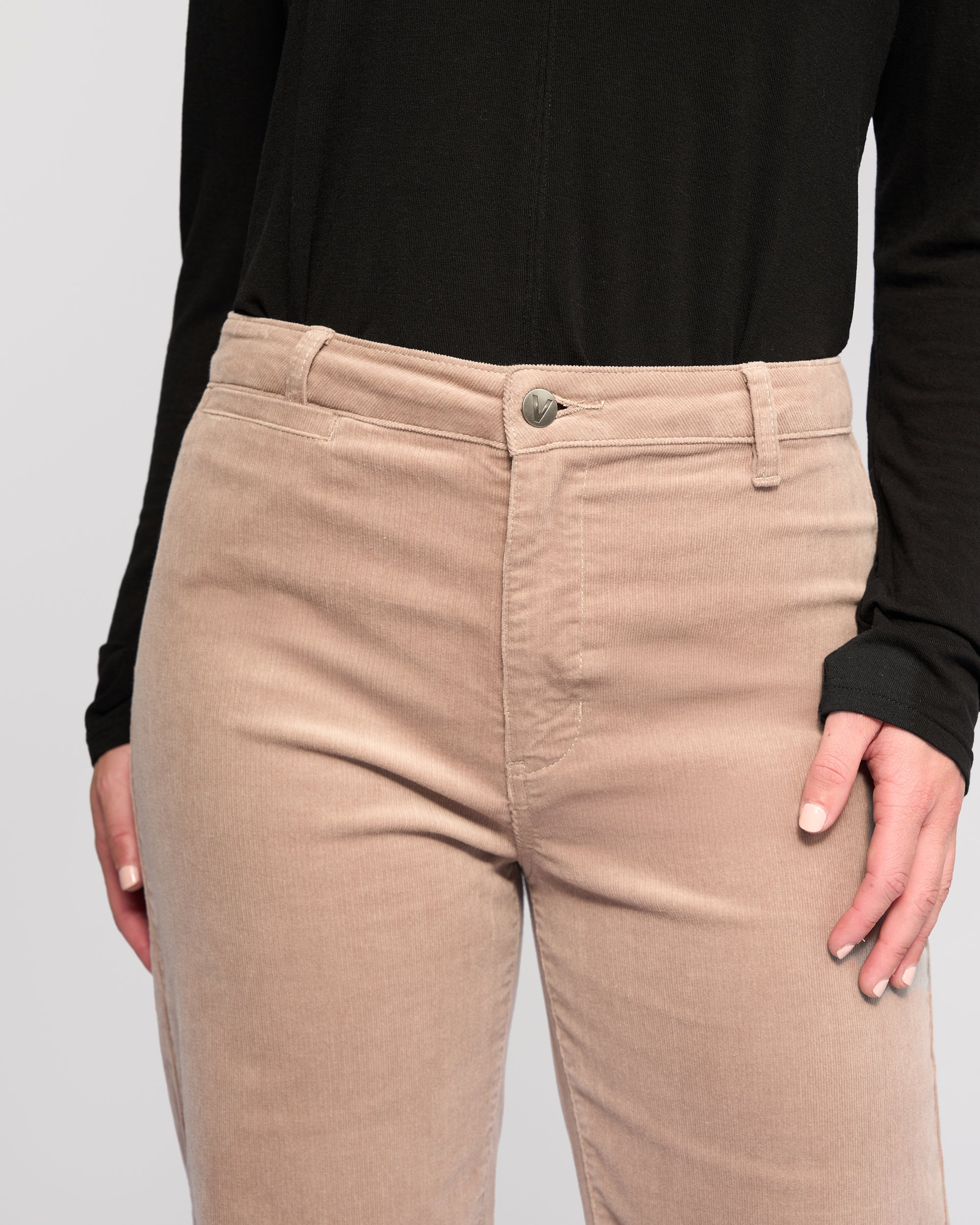 A person wears a black long-sleeve top and Vassalli Market Cord Pant in Twig, with their right hand near the pocket. The image shows only the torso and upper legs.