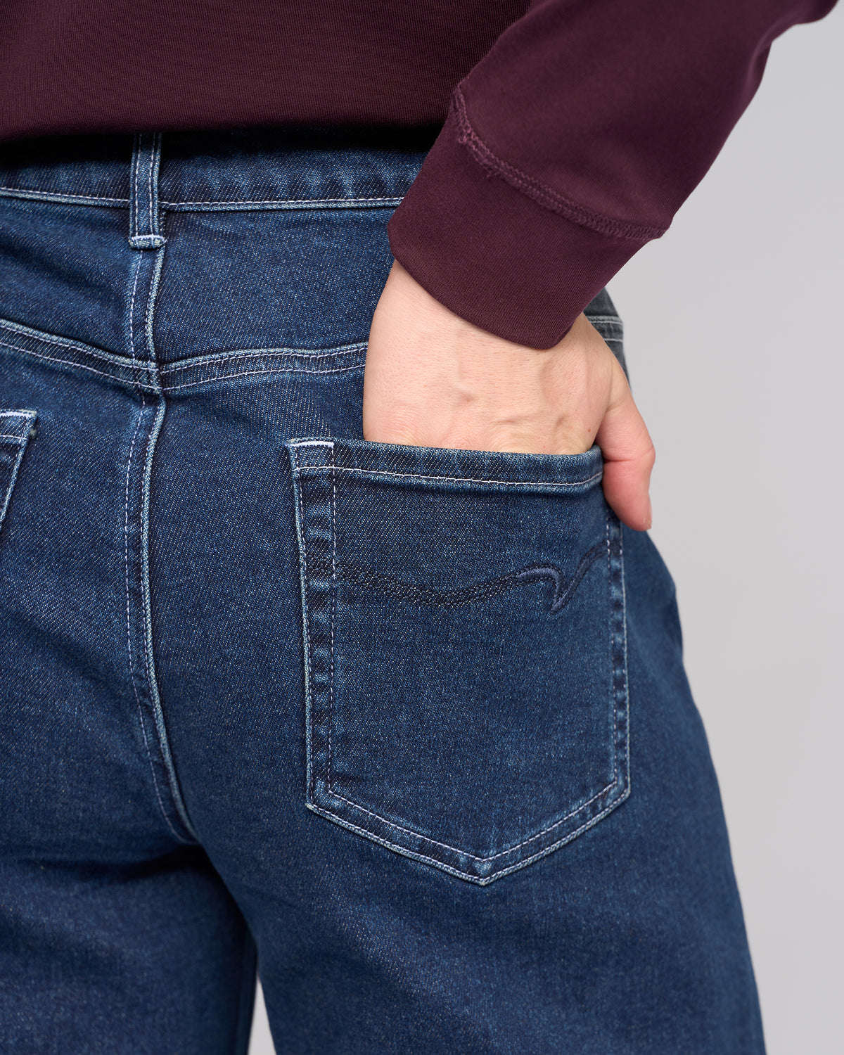 A person wearing Vassalli's Alley Jean - Dark Blue has their right hand in the back pocket, with the image showcasing the jeans' back pocket and part of their torso.