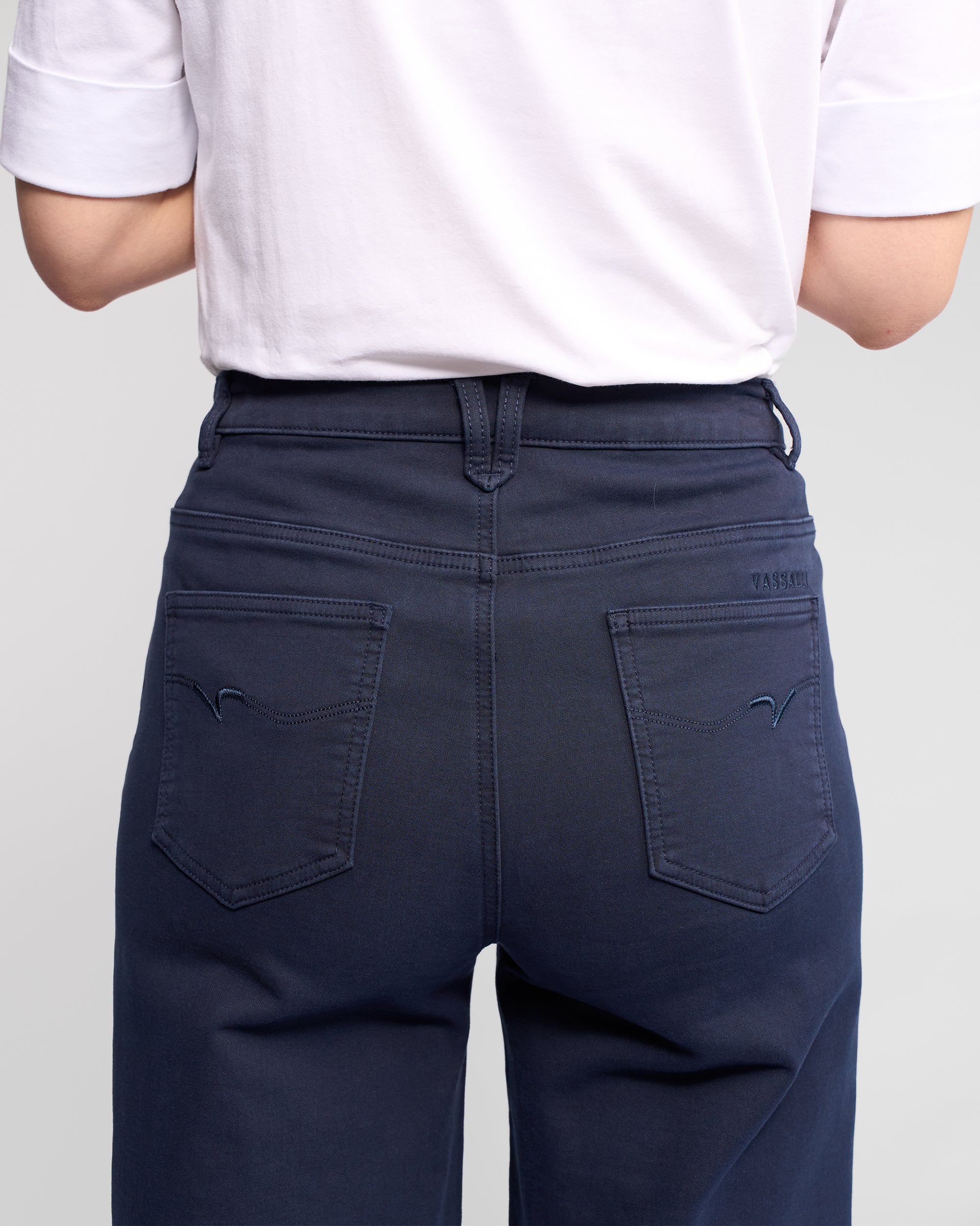 A person is shown from the back wearing Vassalli's Solo Pant - Carbon, with focus on the waist and back pockets of these dark blue wide-leg jeans crafted from soft cotton-tencel stretch fabric.