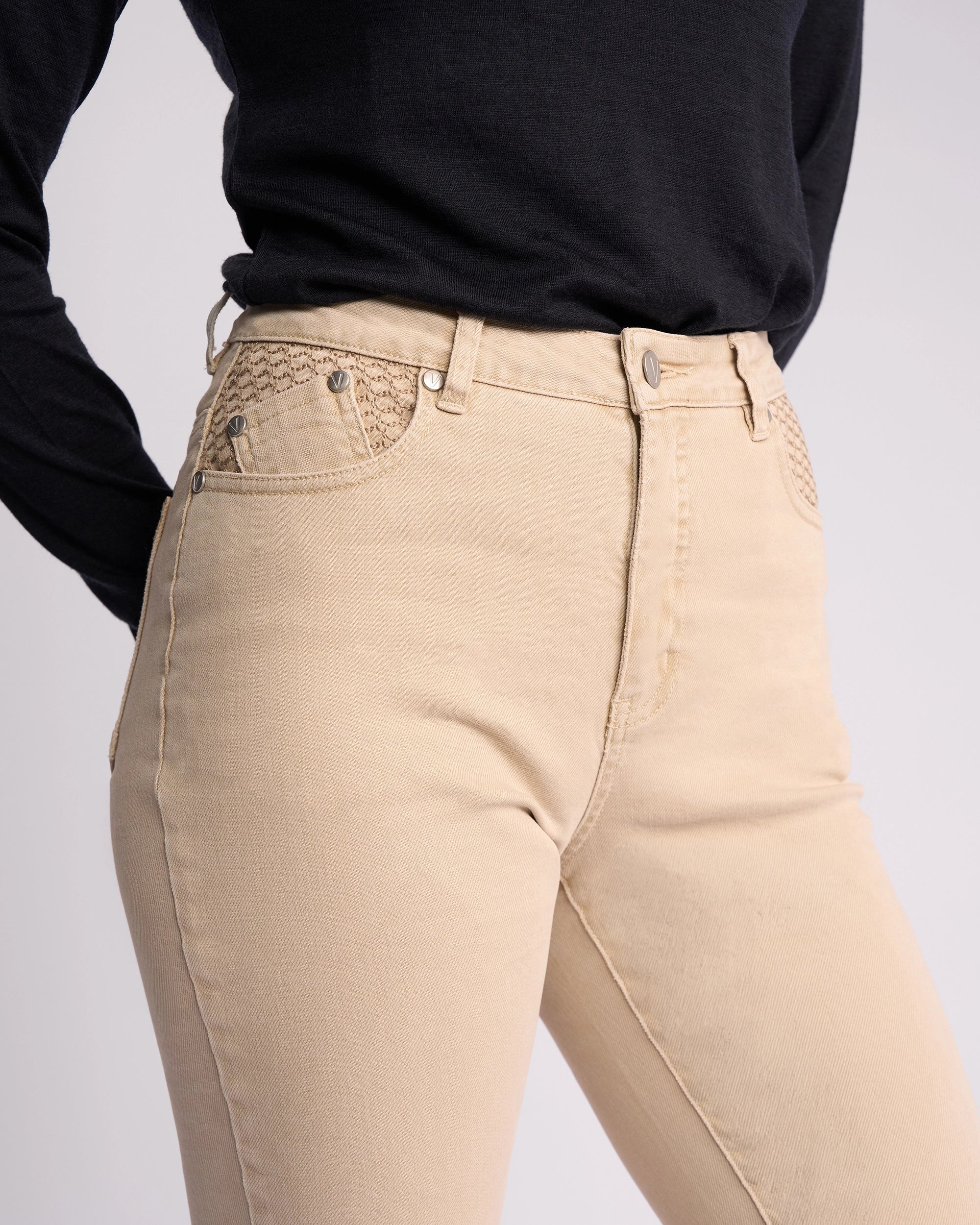 A model wears Vassalli's Reign Jean in Oat Denim, featuring a high-waisted skinny fit and textured pockets, paired with a long-sleeved black top—an ideal pick to elevate women’s denim NZ style.