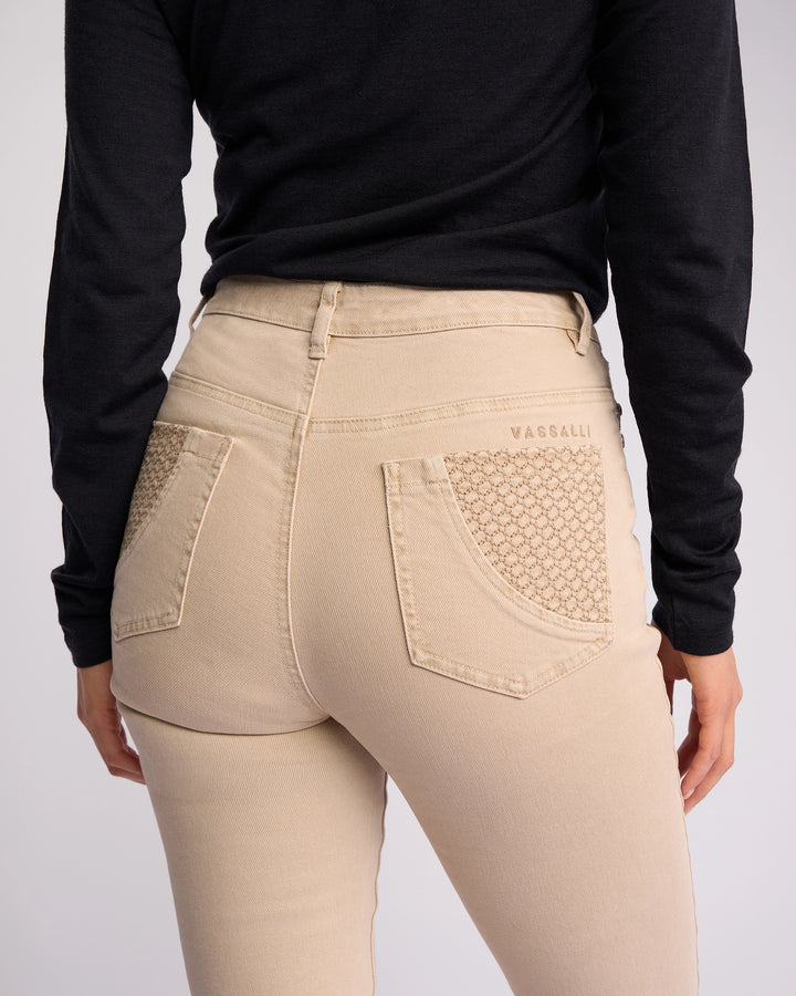 A person shown from behind, waist down, wears Vassalli Reign Jean - Oat Denim with textured back pockets and a black long-sleeve top. The Vassalli brand name appears above the right pocket.