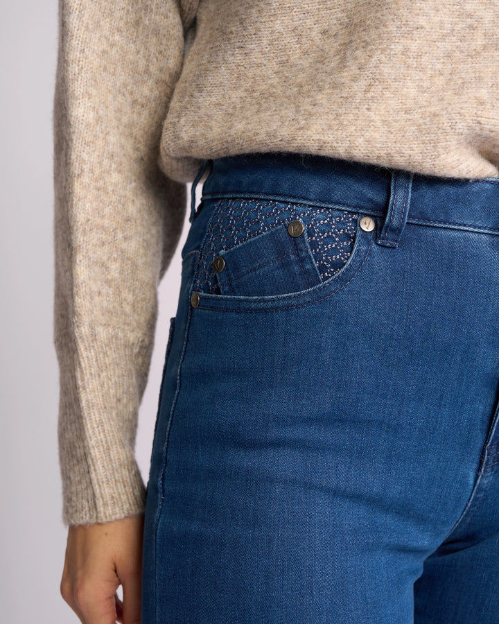 A person wears a beige knit sweater and Vassalli Reign Jean - Plain New Blue, showing only the lower torso and left arm. The high-waisted skinny-leg jeans highlight stylish women’s denim fashion from NZ brand Vassalli.