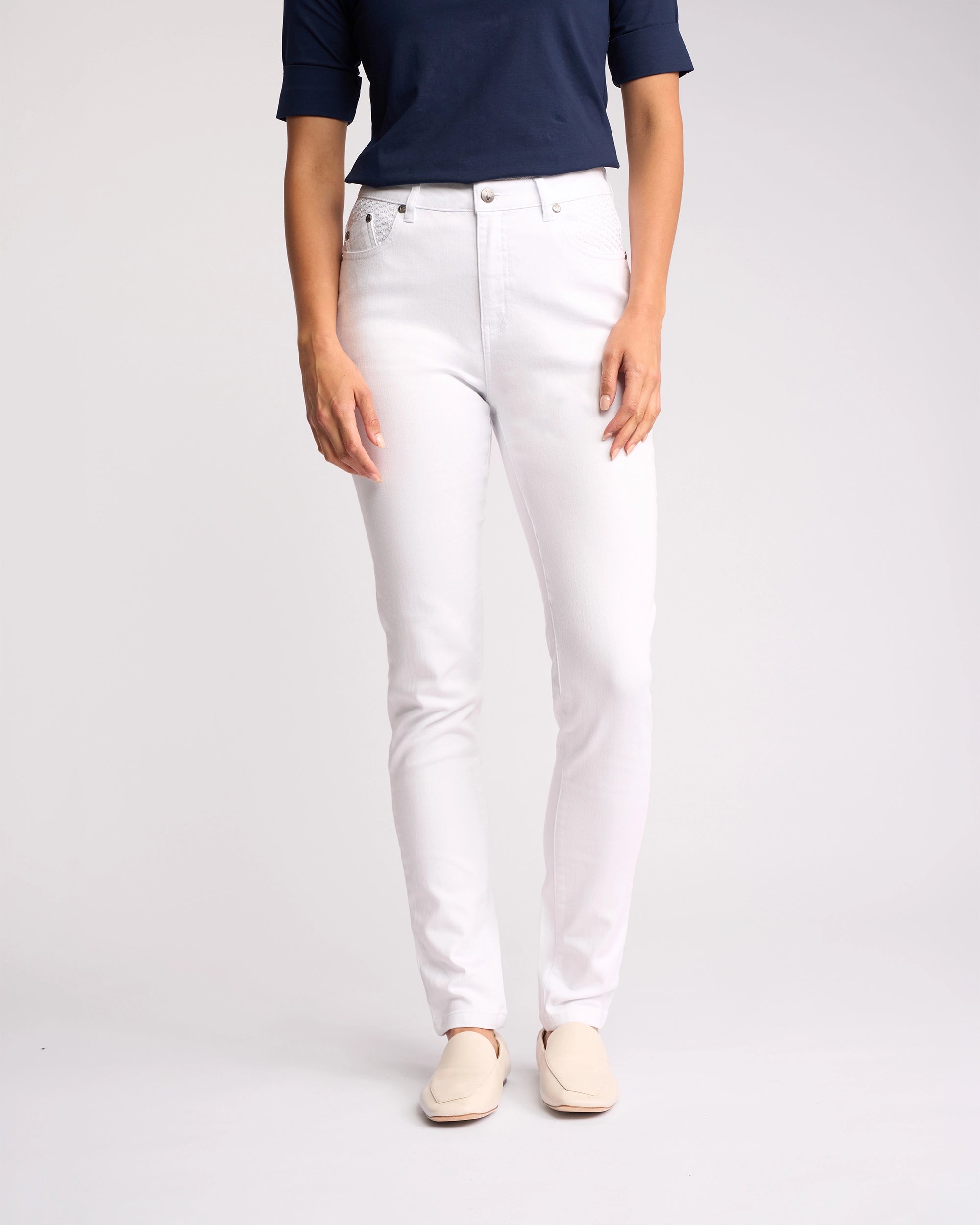 A person models the Vassalli Reign Jean in white denim, paired with a navy short-sleeve top and cream slip-on shoes against a plain background. The photo is cropped from shoulders down—ideal inspiration for women’s denim NZ style.