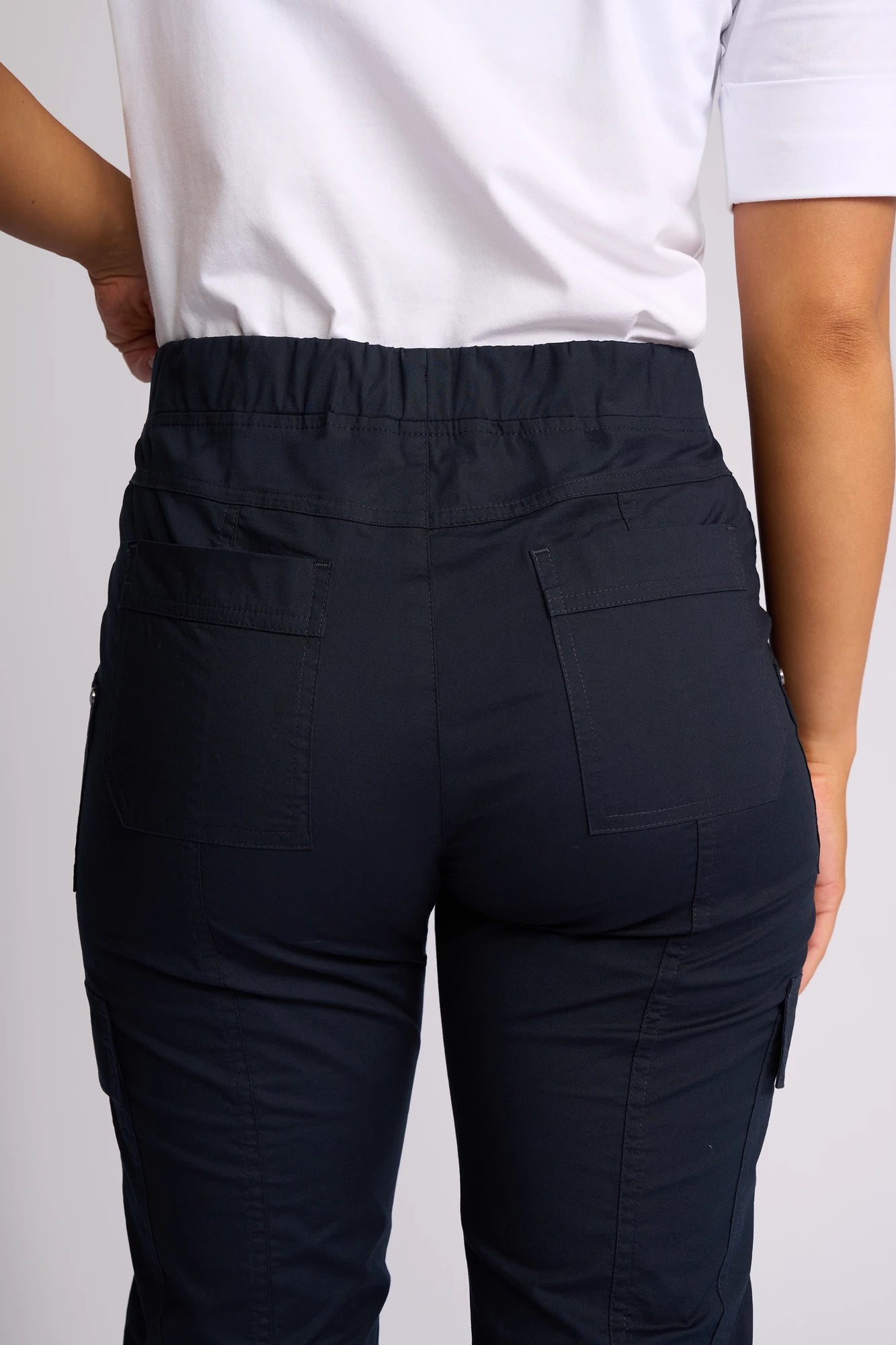 A person is shown from the back wearing a white shirt and Vassalli’s Wave Pant in navy, highlighting the stretch cotton waistband and pocket details.