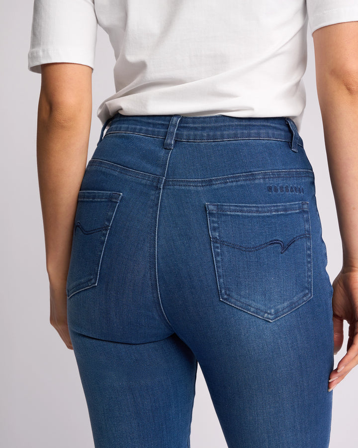 A person is shown from the back wearing Vassalli’s Icon Jean - Blue Denim, highlighting the skinny-leg jeans' back pockets and seam details with a white t-shirt.