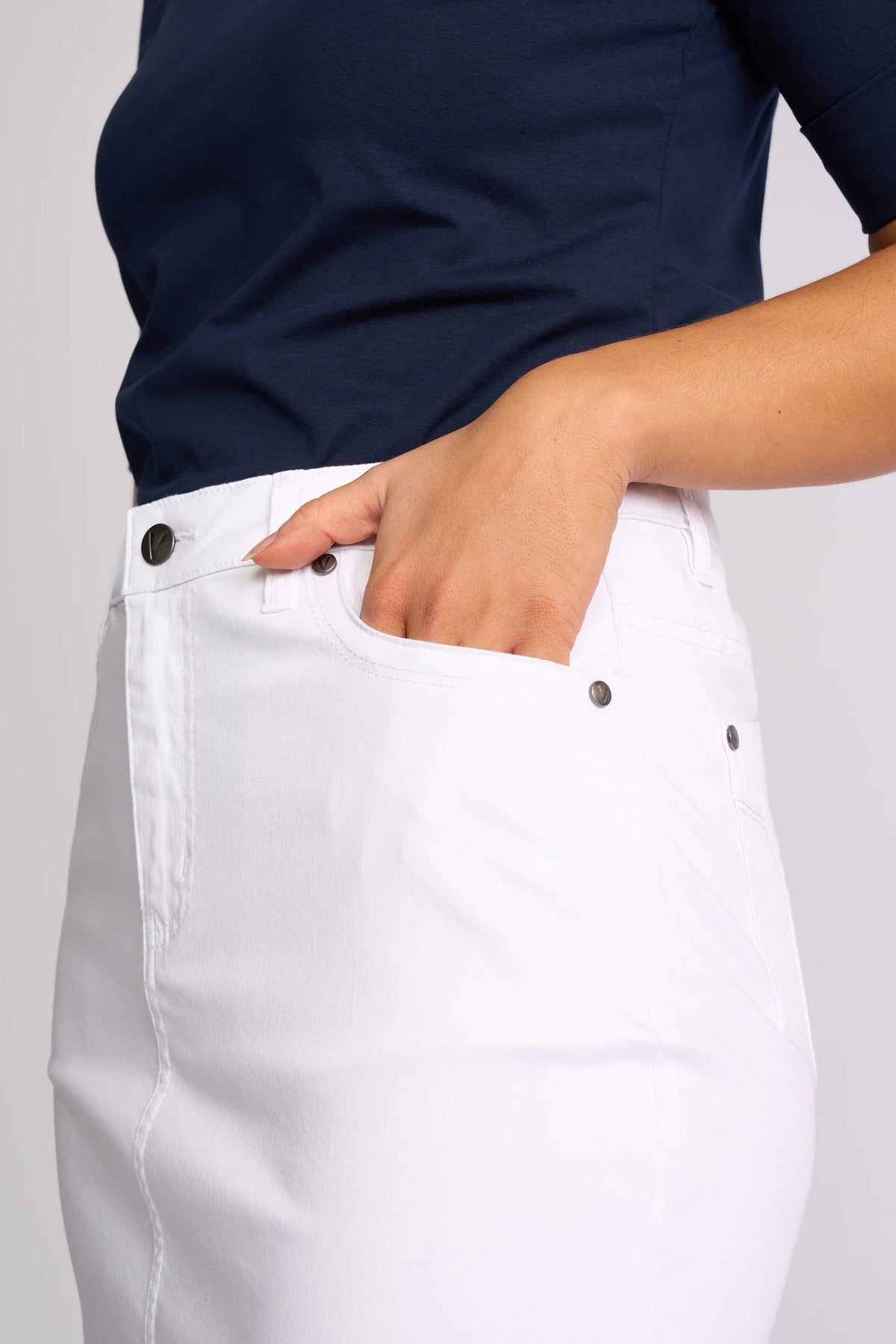 A person is shown from the torso to upper legs, highlighting the Vassalli Tilt Skirt in white and their right hand placed in the front pocket.