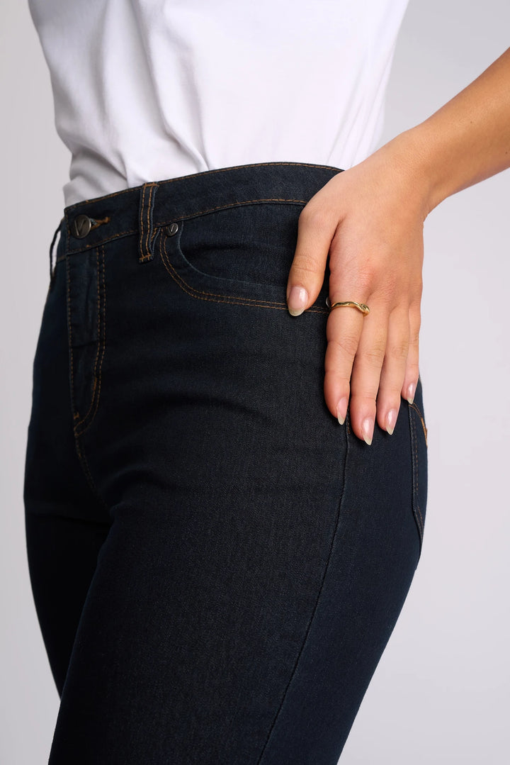A person wearing a white shirt and Vassalli’s Alfa Short - Indigo Denim (Contrast Stitch) stands with one hand resting on their hip, displaying a gold ring on their finger.
