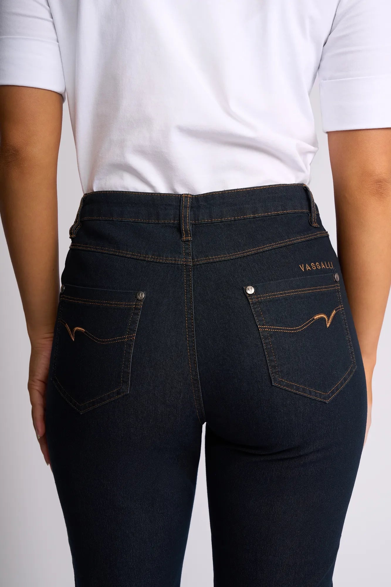 A person wearing a white shirt and dark blue Vassalli Alfa Short - Indigo Denim (Contrast Stitch) is shown from the back, highlighting the fit and design of the shorts’ back pockets.