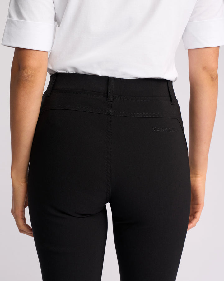 A person is shown from the back wearing Vassalli’s Concept Pant in black, paired with a white short-sleeve shirt, highlighting the waist and upper legs.
