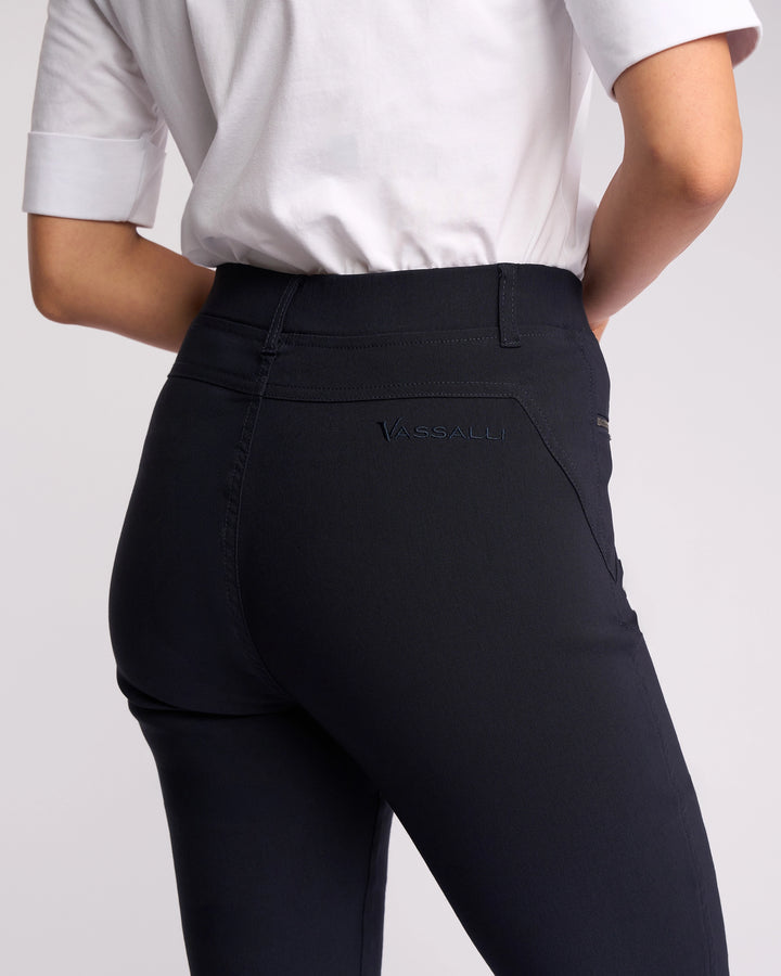 A person wearing a white short-sleeve shirt and Vassalli's Concept Pant in navy, shown from the back waist down. The pants feature "VASSALLI" embroidered on a back pocket.
