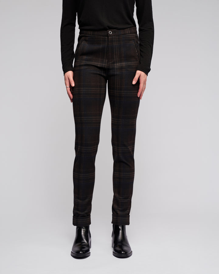A person, shown from the shoulders down against a plain background, wears a black long-sleeve top, Vassalli Style Pant - Hugo in a check pattern, and black ankle boots.